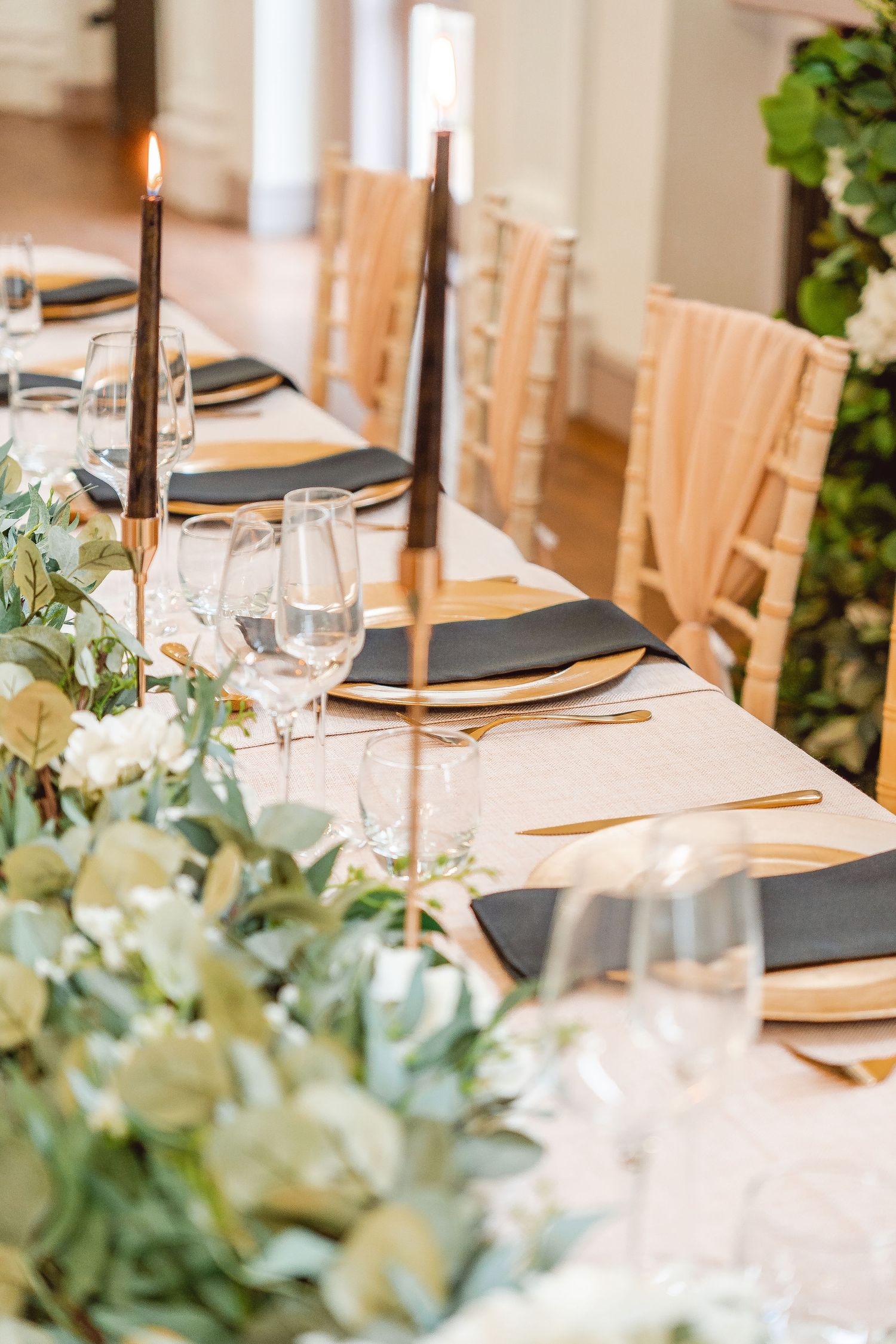 details of table set up with black taper candles and napkins, gold plates, cutlery and candle holders