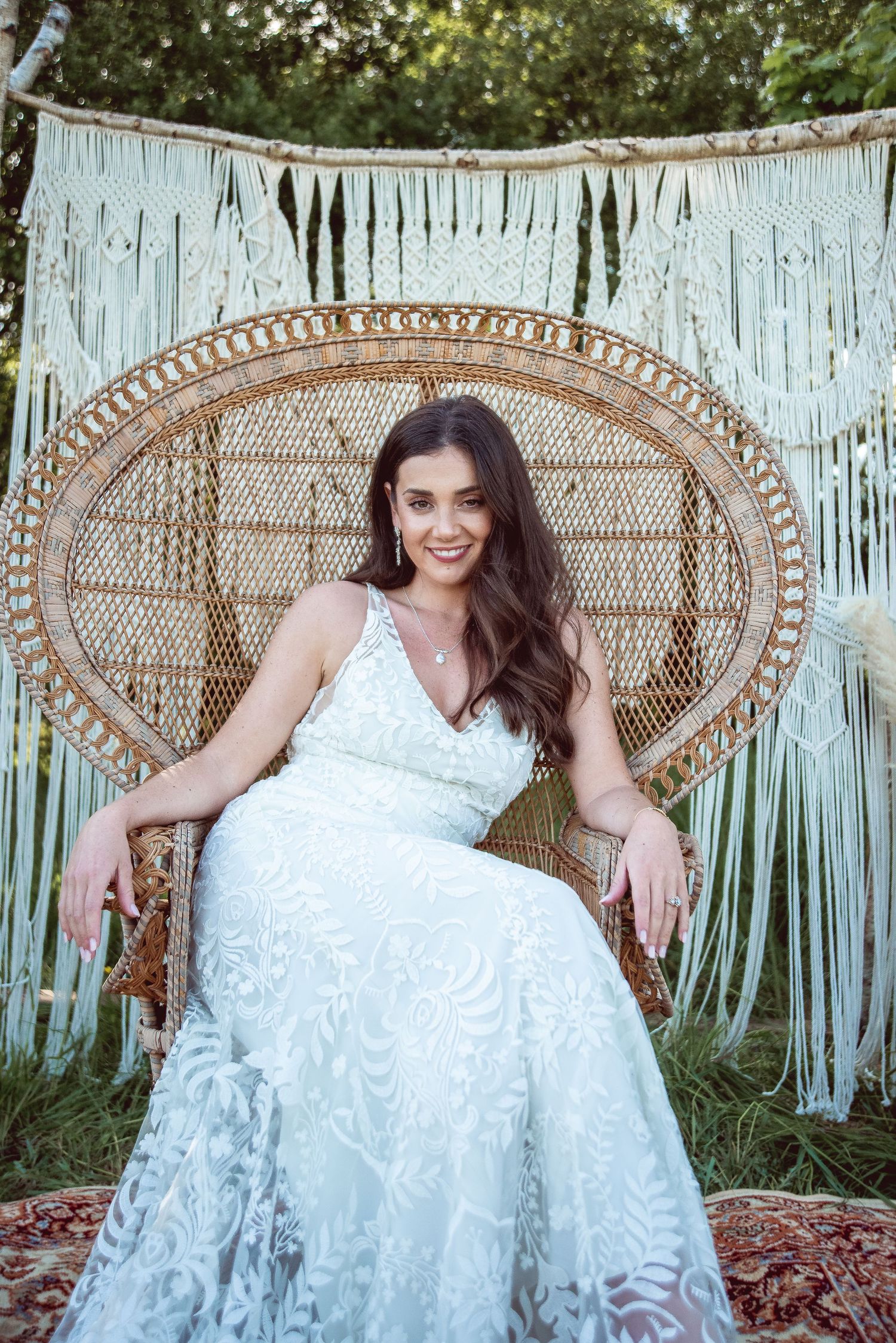 Boho bridal portrait featuring a woven peacock chair and white macrame wall hanging.