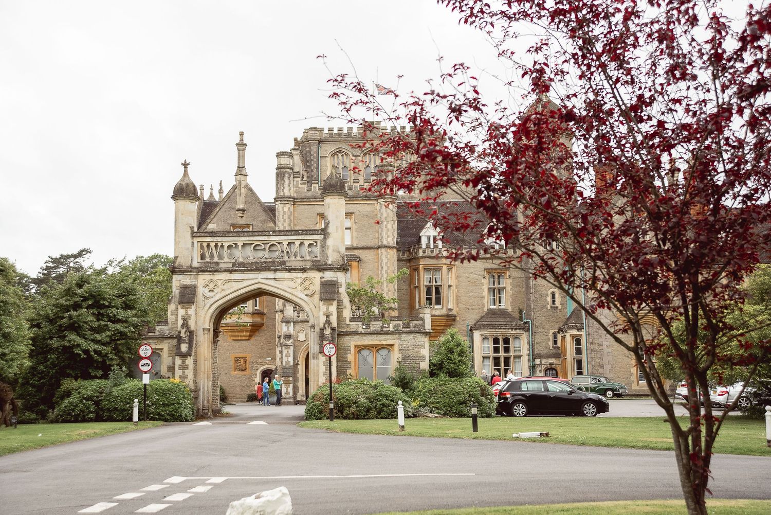 A scenic view of a historic stone church and grounds with red maple trees and winding pathways.