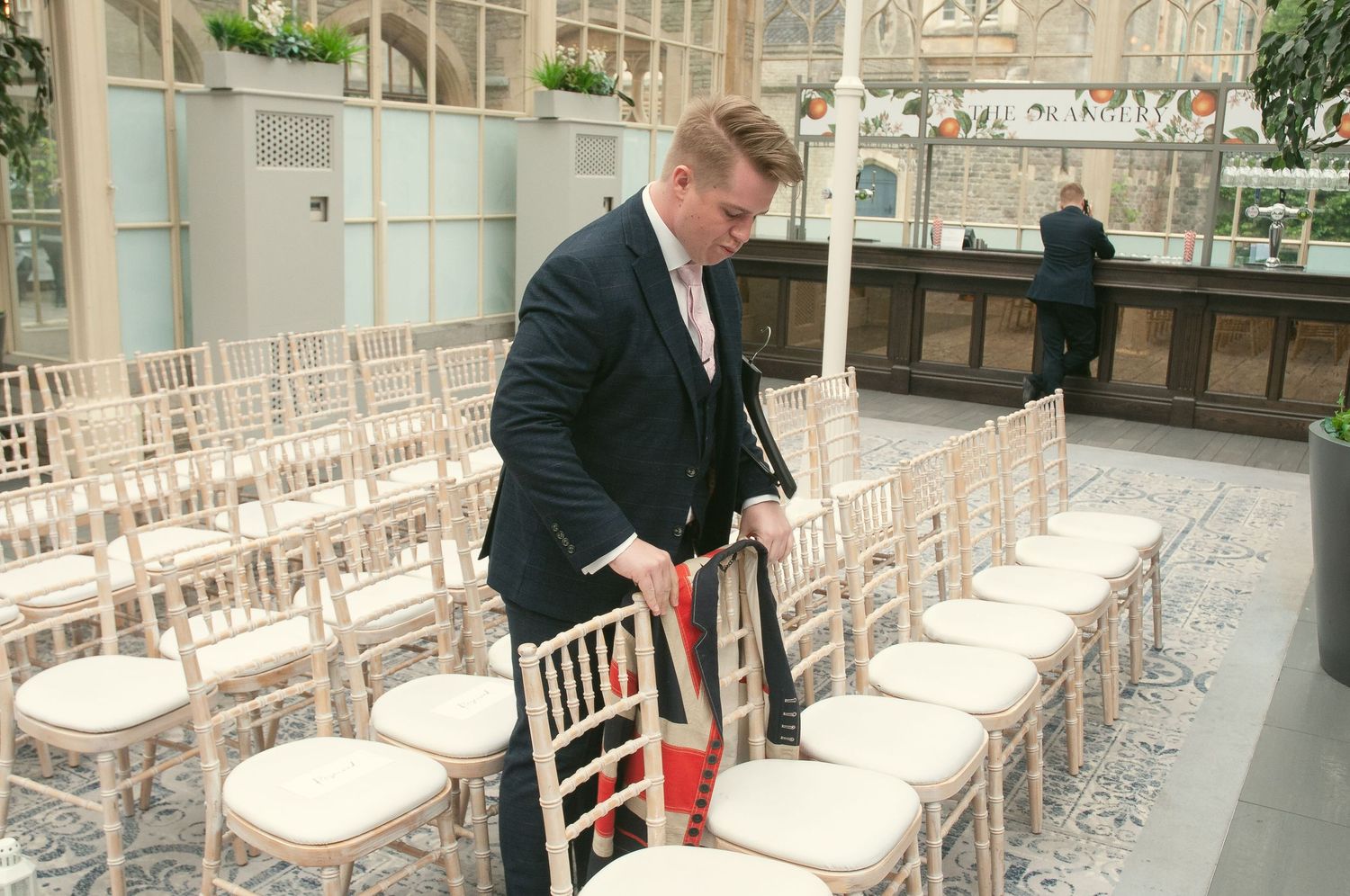 Wedding venue staff member arranging white Chiavari chairs for the ceremony.