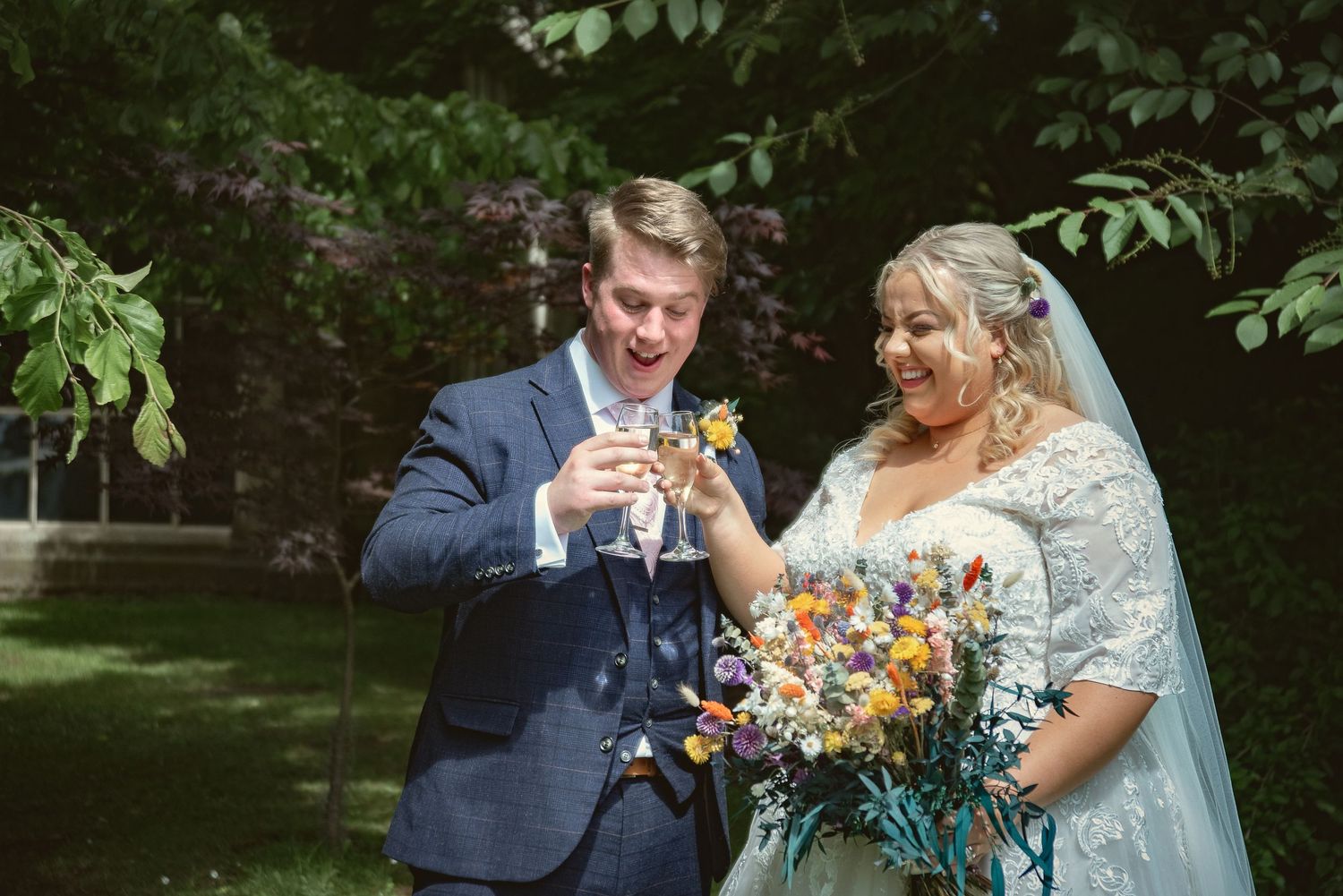 Happy couple toasting with champagne in garden setting after their wedding ceremony.