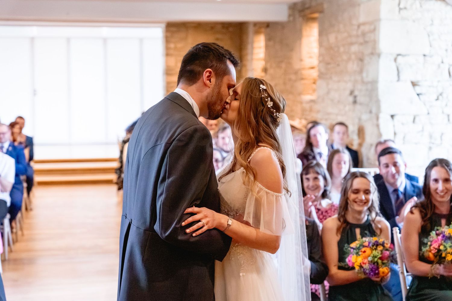 Wedding couple and guests celebrate with joyful dancing at an elegant indoor reception venue.