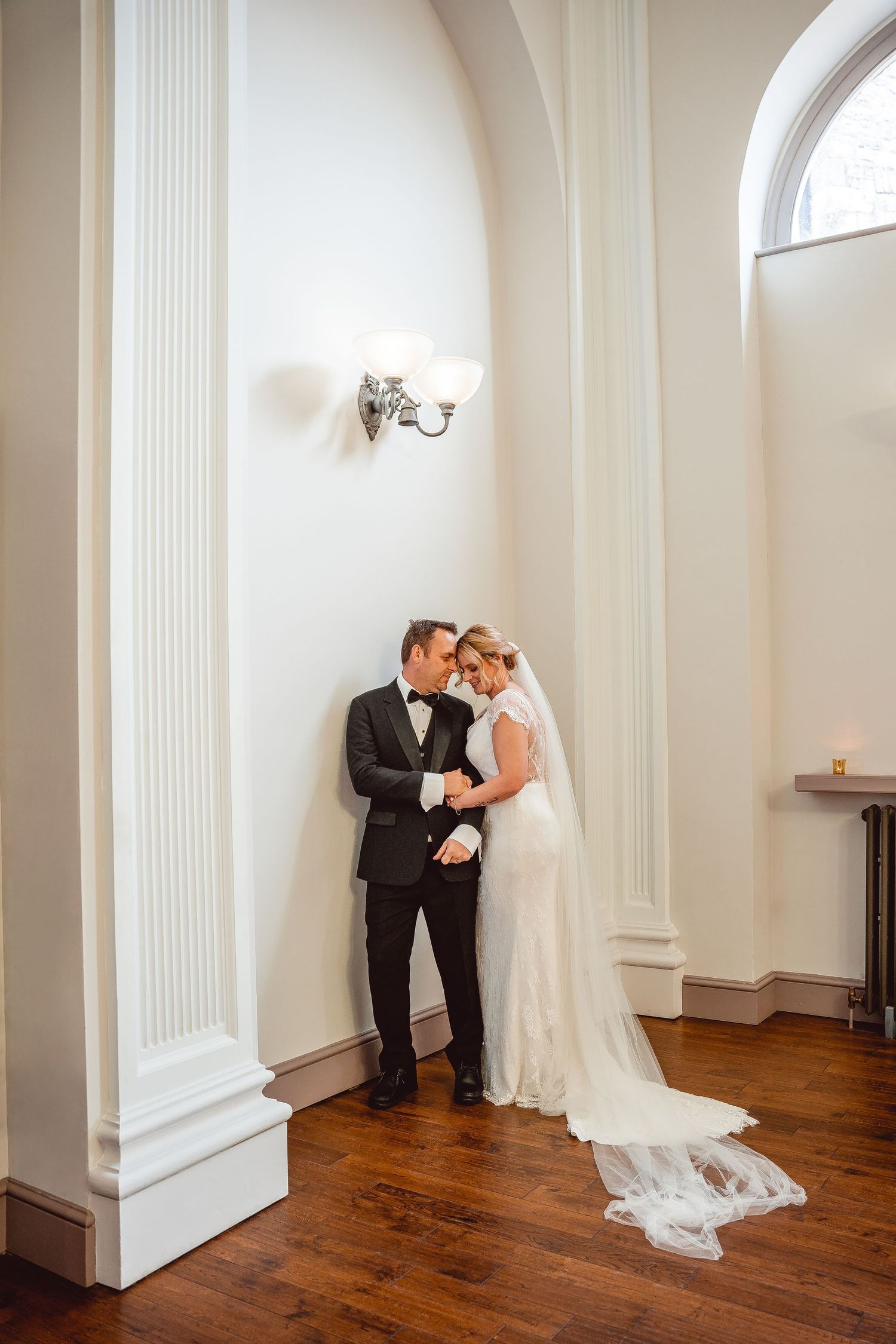 Full length portrait of Bride and Groom having a quiet moment in the corner of the room