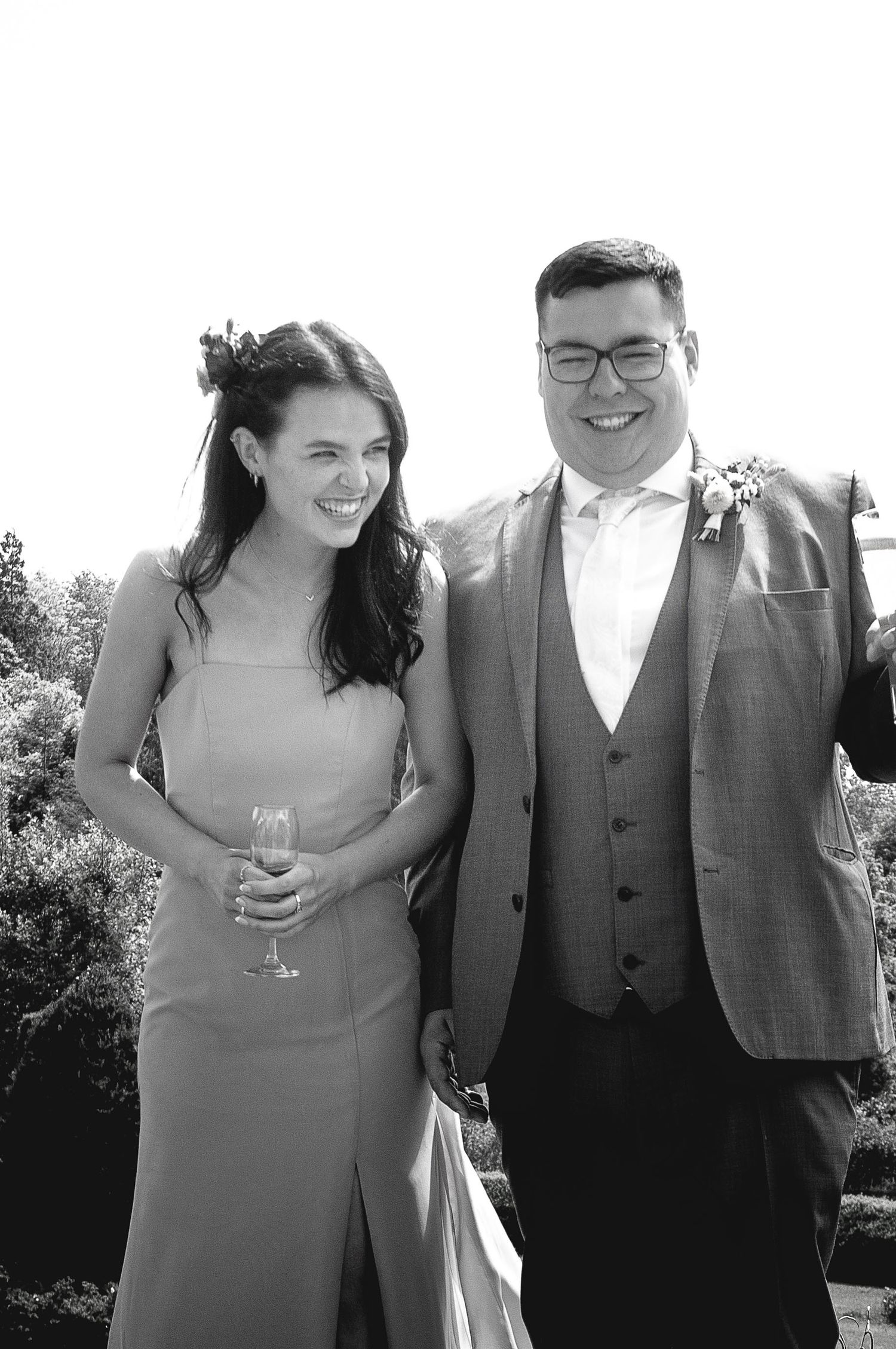 Wedding guests in formal attire sharing a candid moment with drinks.