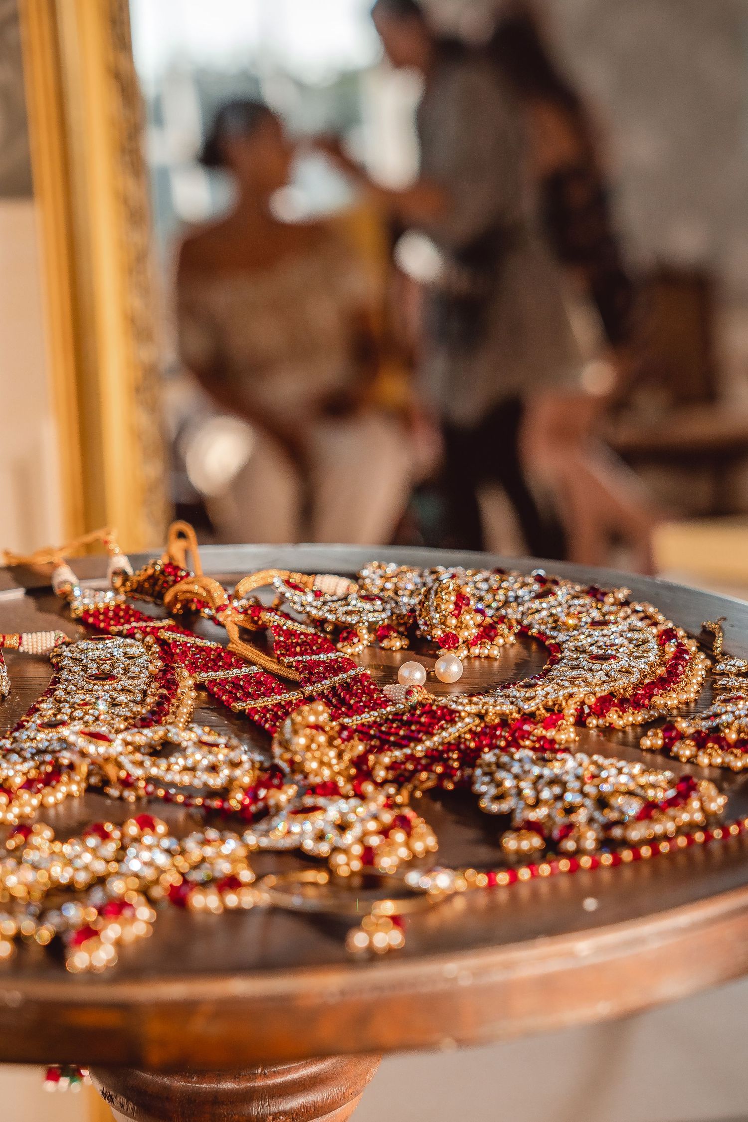 Sikh Red Wedding jewellery close up with out of focus bride getting ready in the background