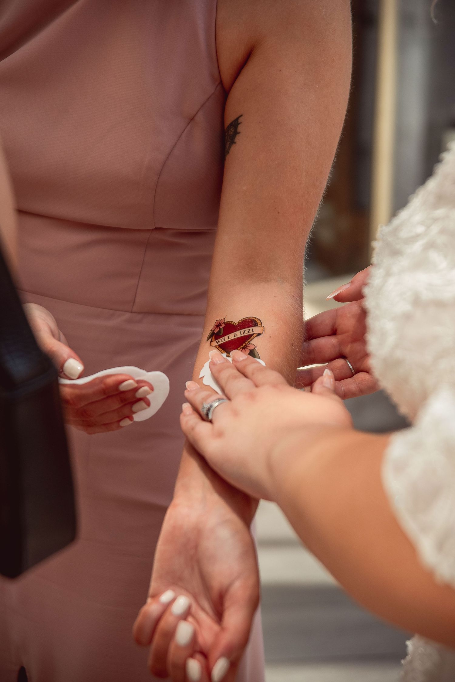 Close-up of hands exchanging rings during a wedding ceremony with a red butterfly detail.
