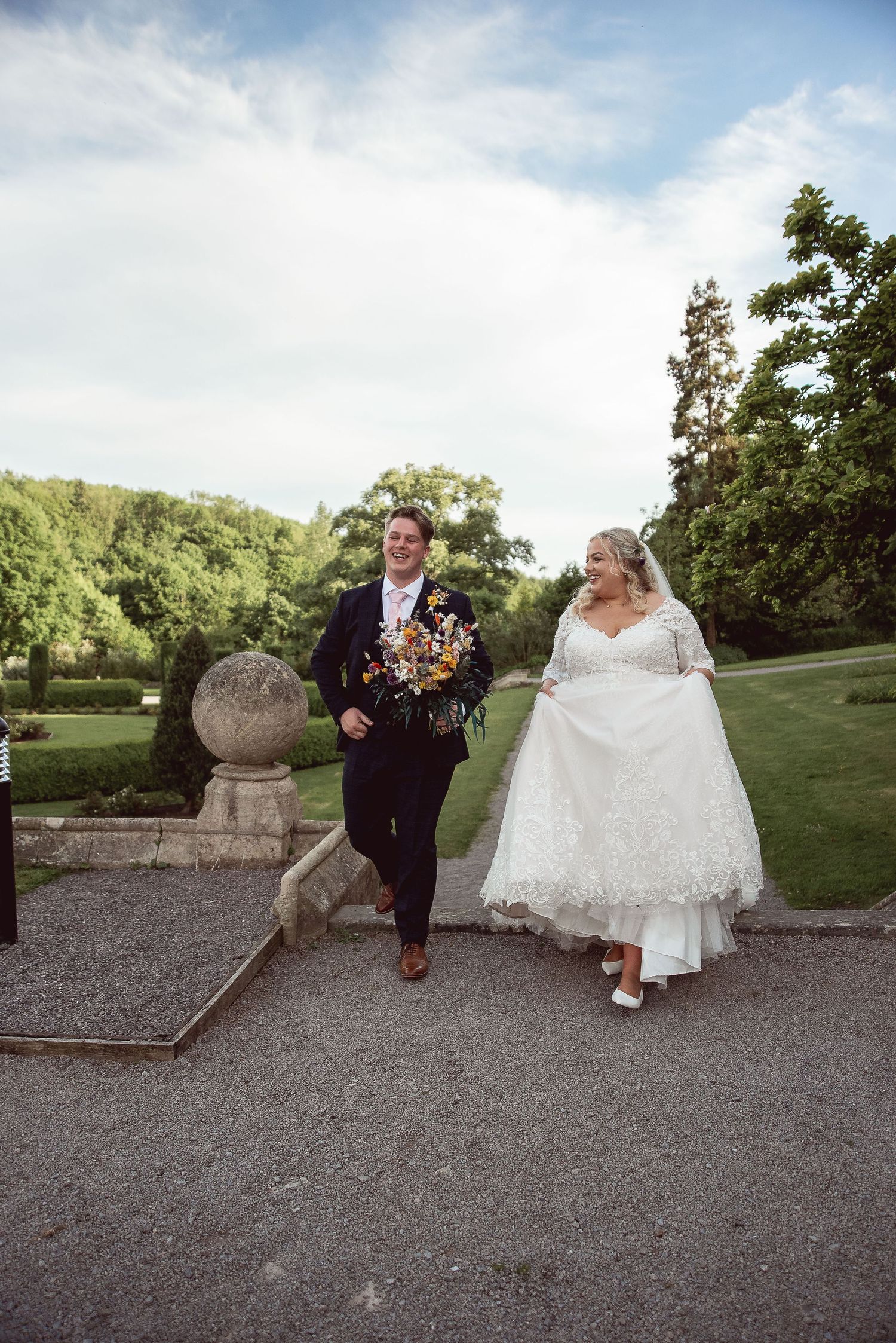 A playful wedding photo session on stone steps with a castle garden backdrop.