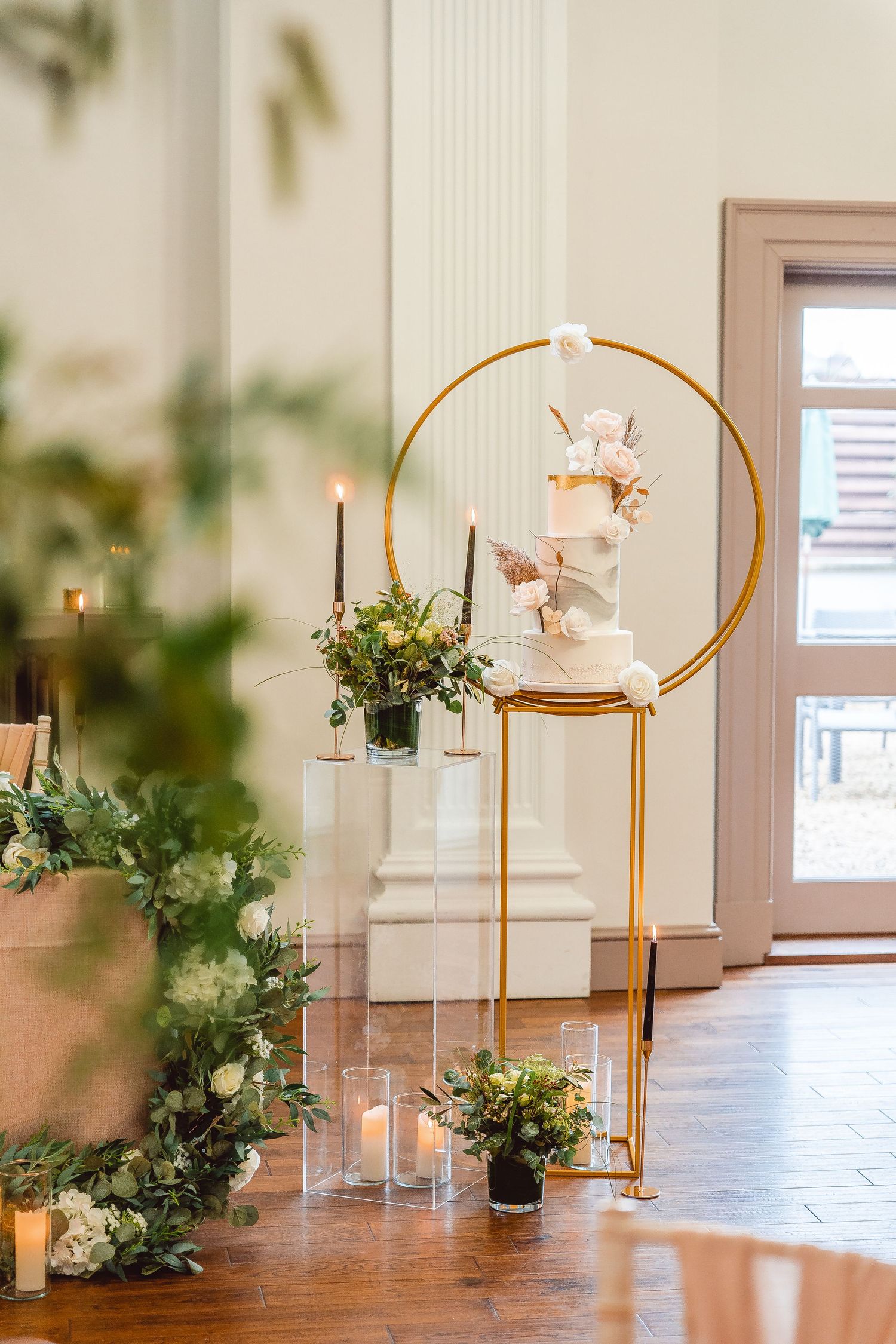 Full view of 3 tier cake and gold circular cake stand on a gold plinth