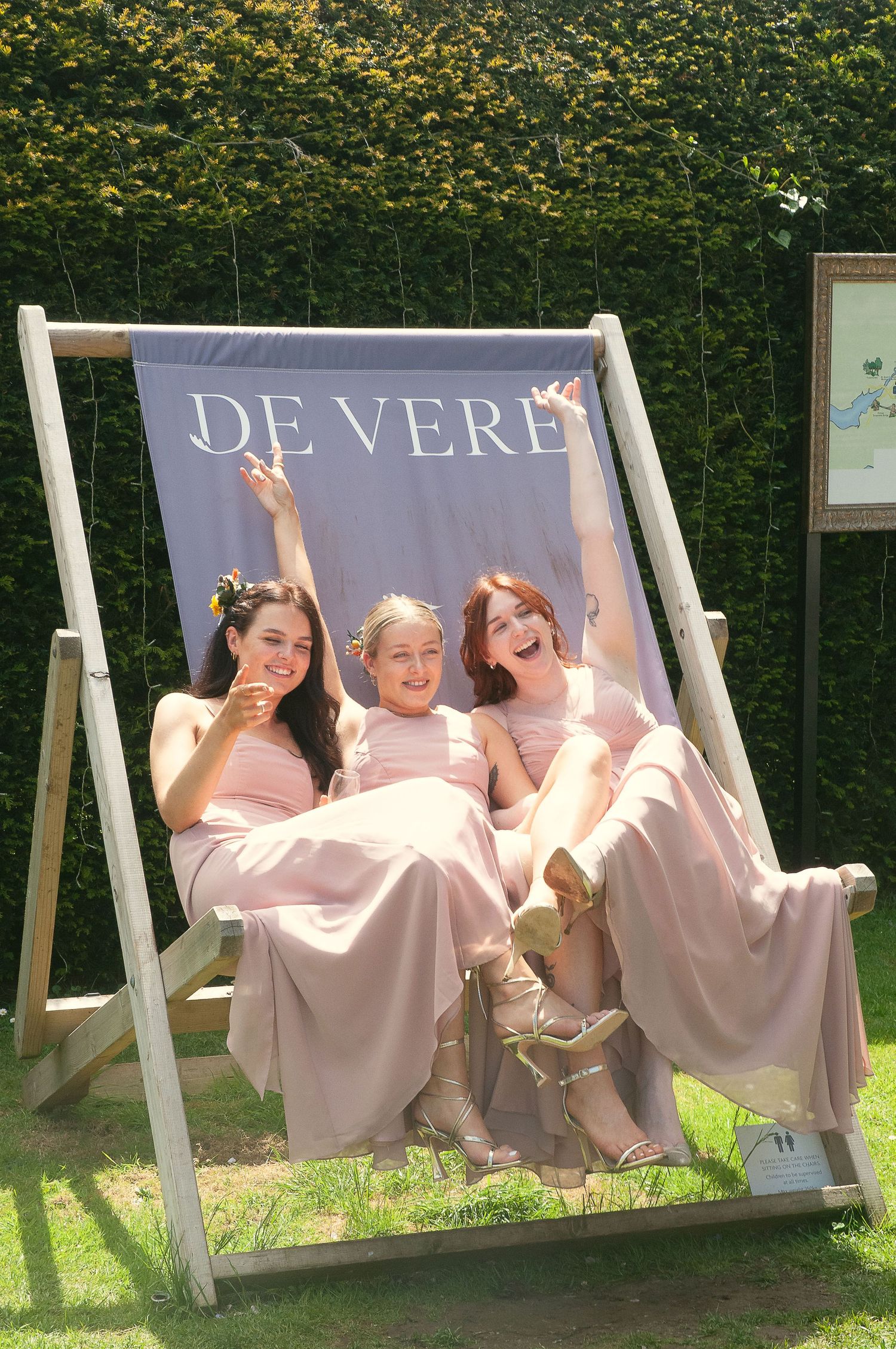 Bridesmaids in pink dresses having fun on a garden swing set.