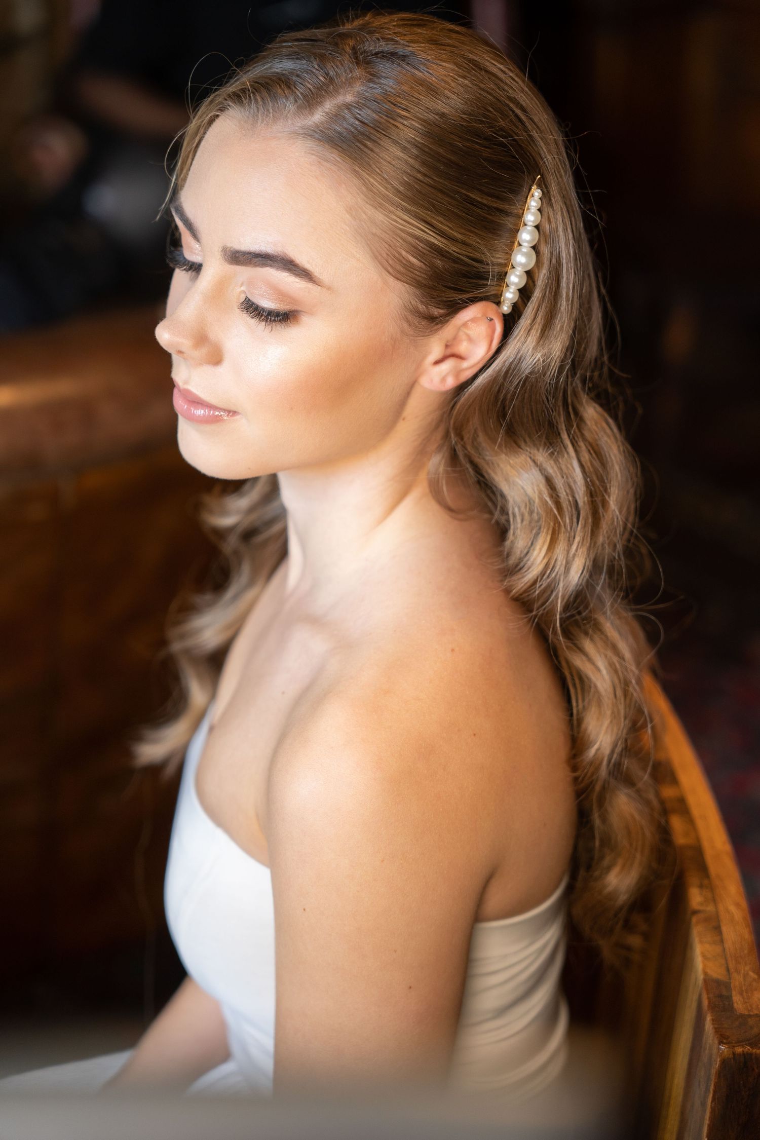 Bride close up as she's getting make up done with Hollywood glamour wavy hair and pear clip