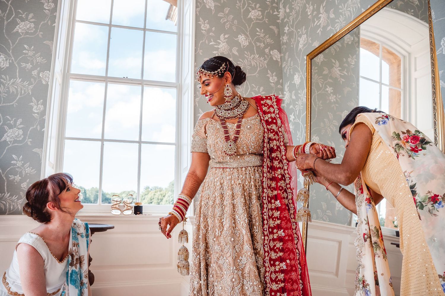 Low angle of Bride getting ready being helped by bridesmaids with Indian saree