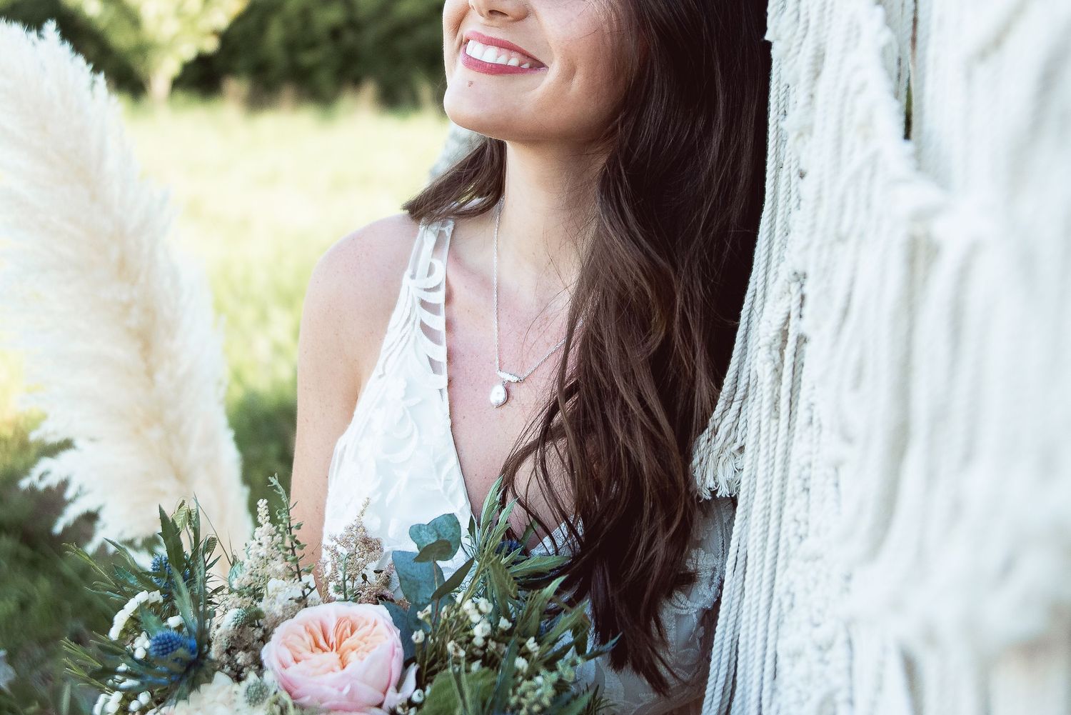 Candid bridal moment with peach and blue floral bouquet against macrame backdrop.