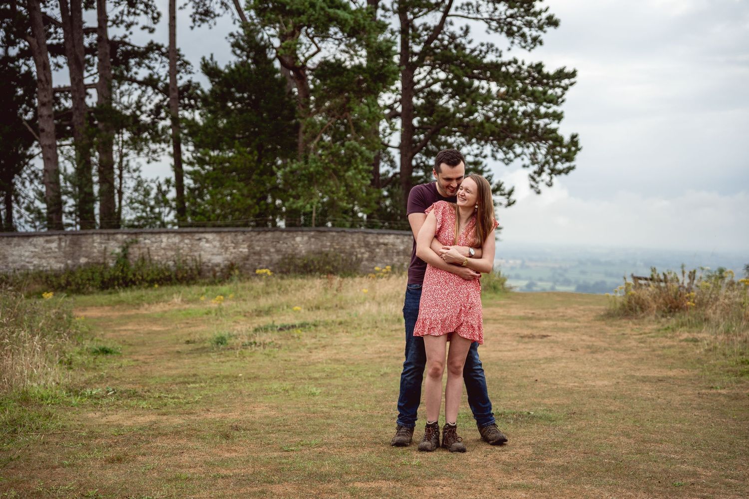 wide shot of couple embracing, male embracing from behind