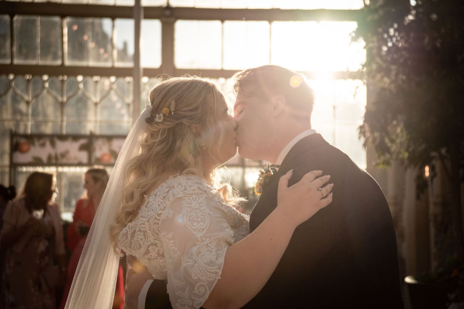 A romantic sunset kiss between newlyweds in a beautifully lit indoor venue.