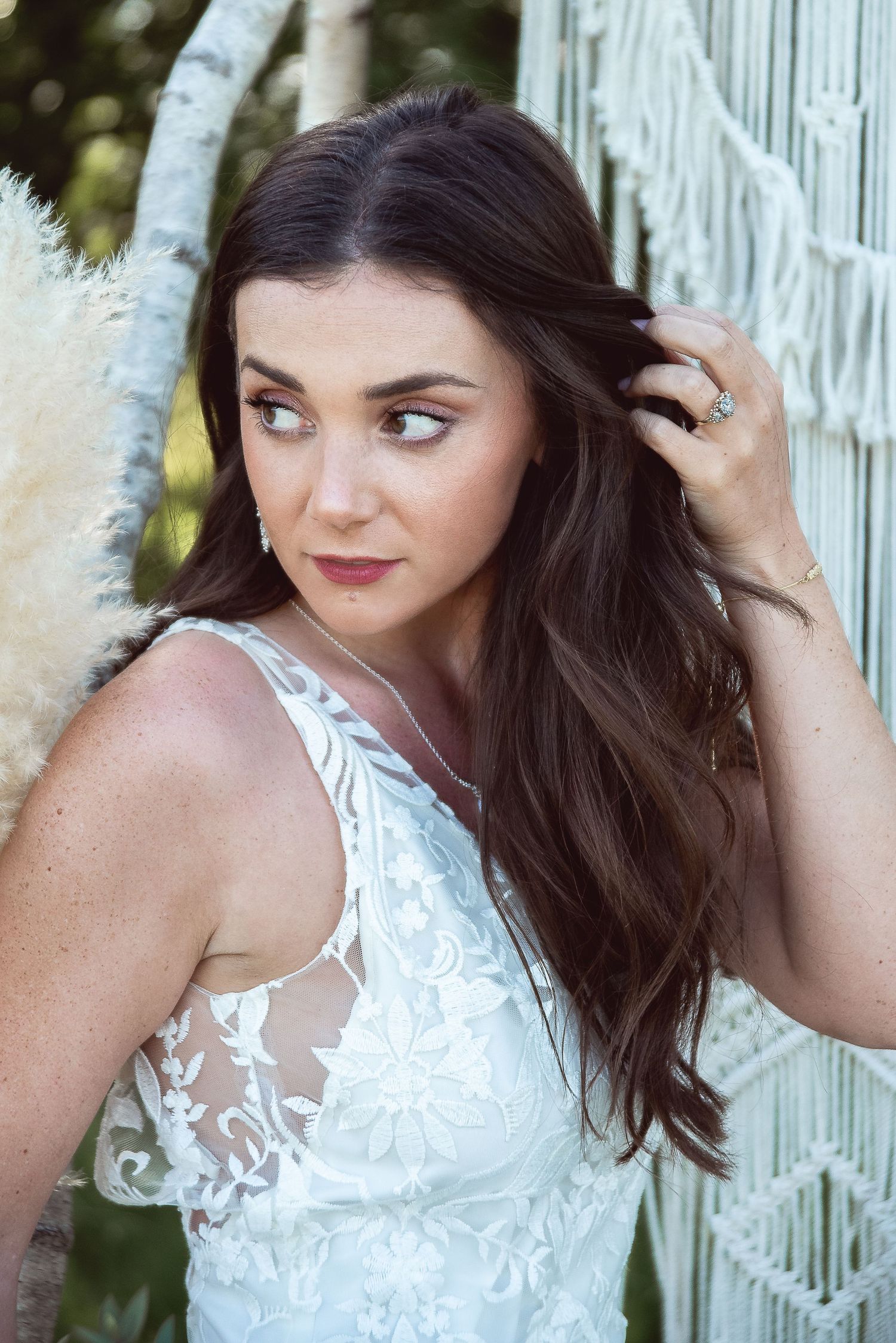 Close-up bridal portrait showing intricate lace details and natural styling against white macrame.