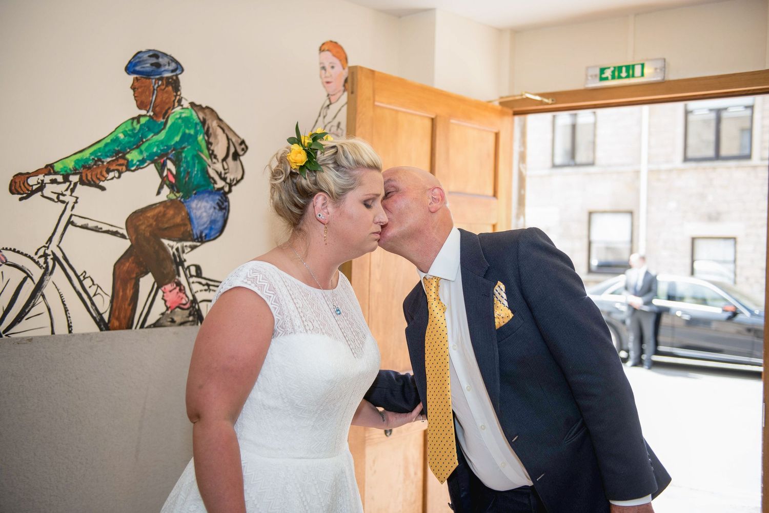 Bride looking nervous and welcoming her dad. Dad is kissing her on the cheek