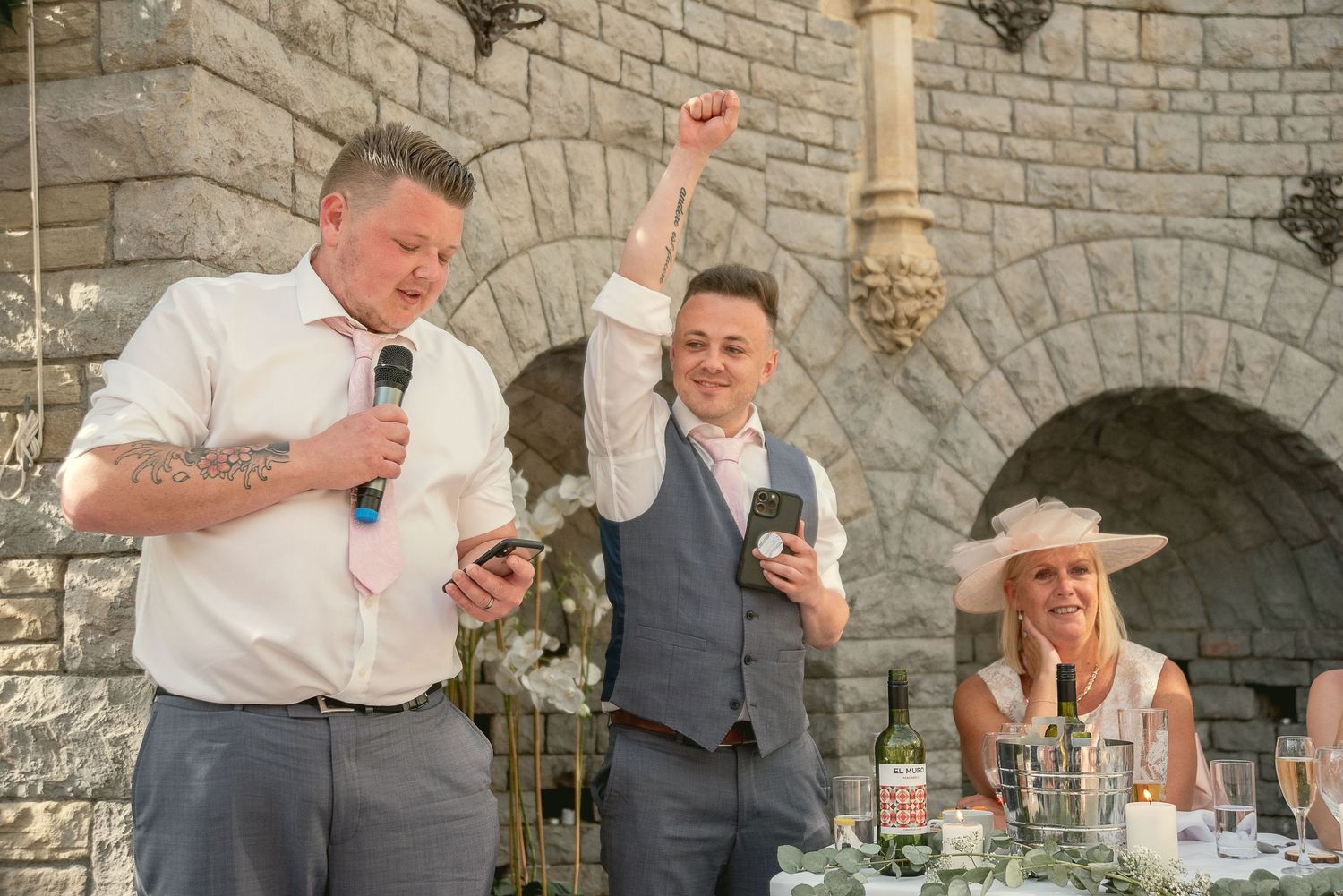 Wedding guests enjoying toasts and speeches at stone venue reception.