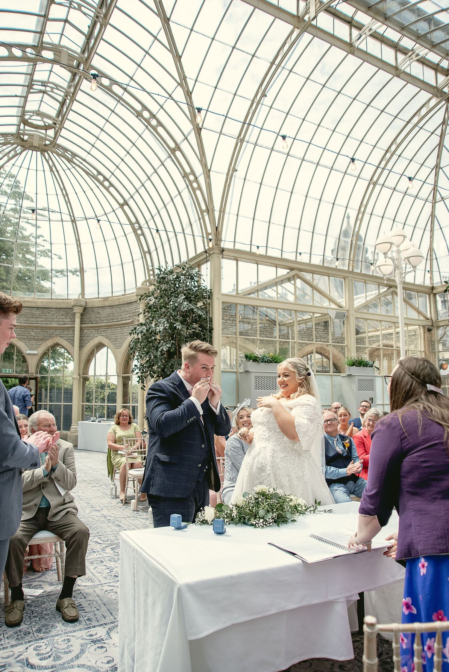 Wedding ceremony under a stunning glass conservatory roof with gothic architectural details.