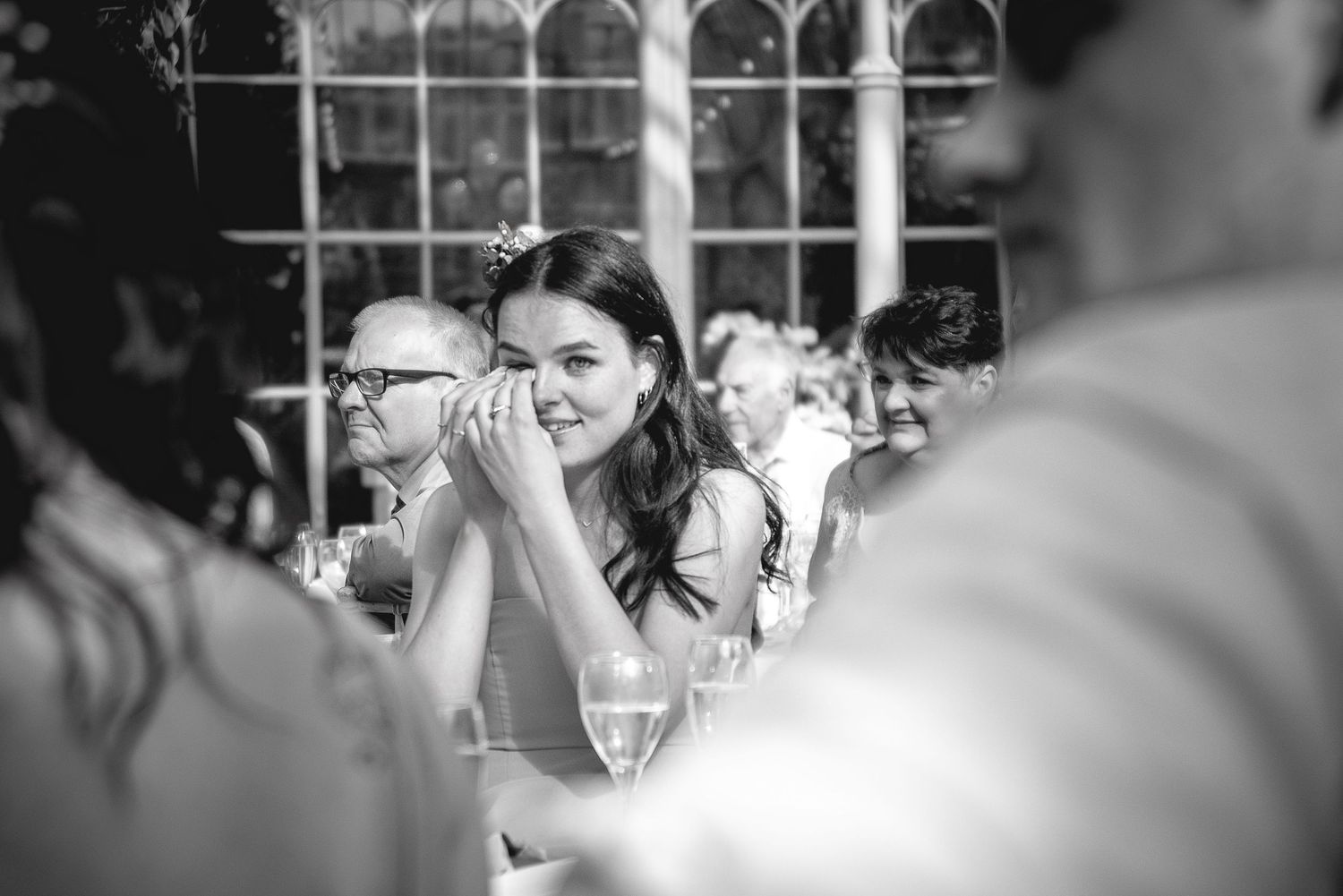 Wedding reception guests seated at long tables in an elegant stone archway venue.