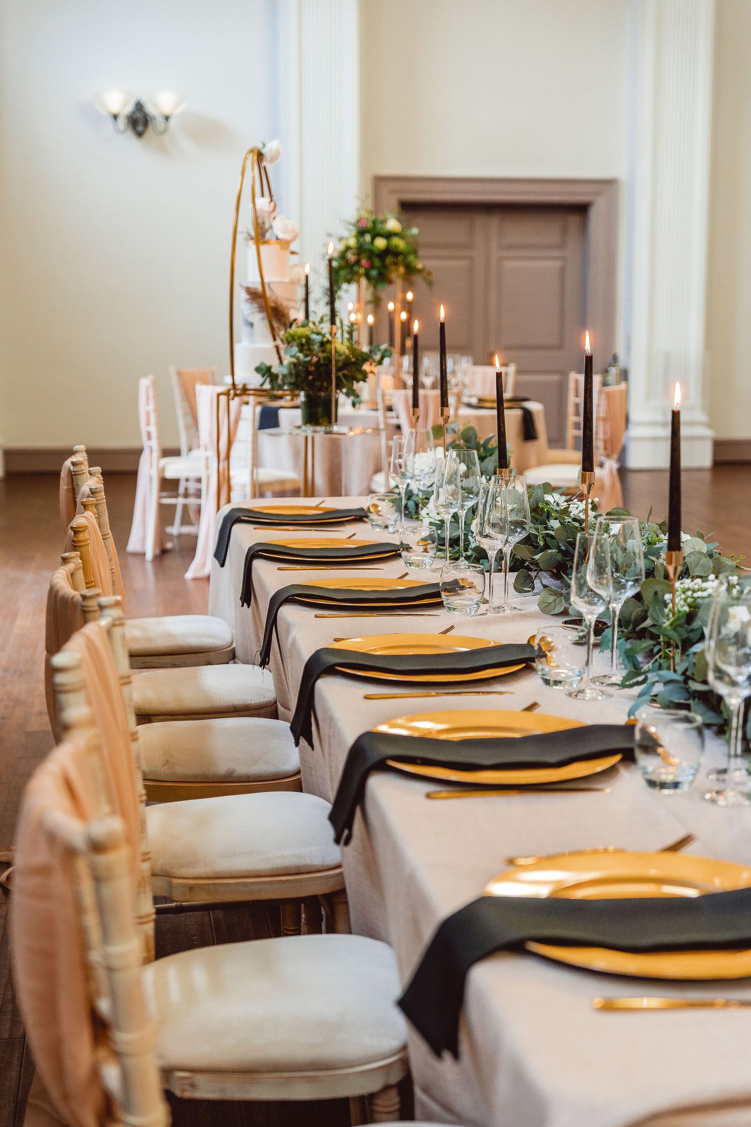 details of table set up with black taper candles and napkins, gold plates, cutlery and candle holders