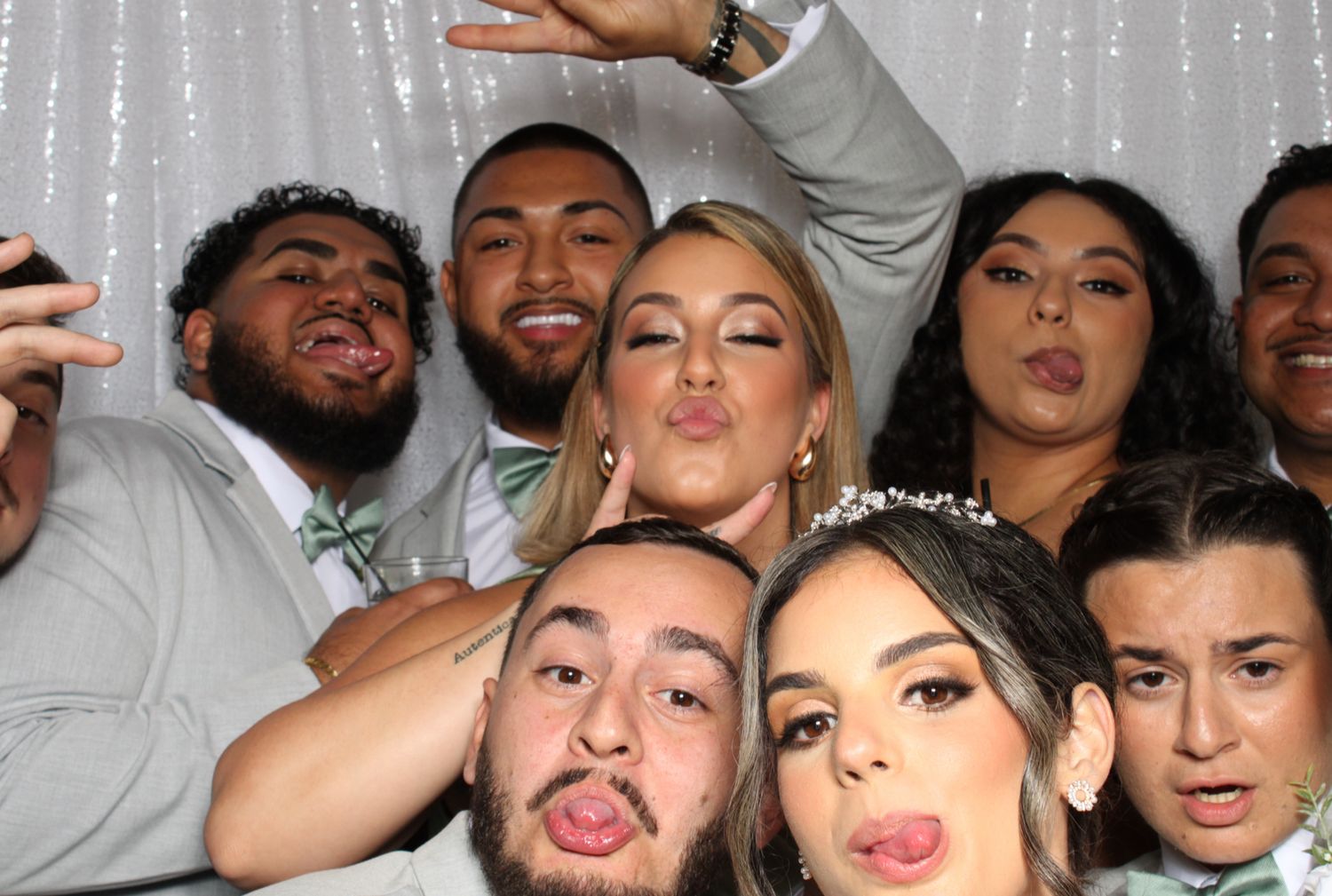 Group photo booth shot with people making playful expressions and poses against a silver backdrop.