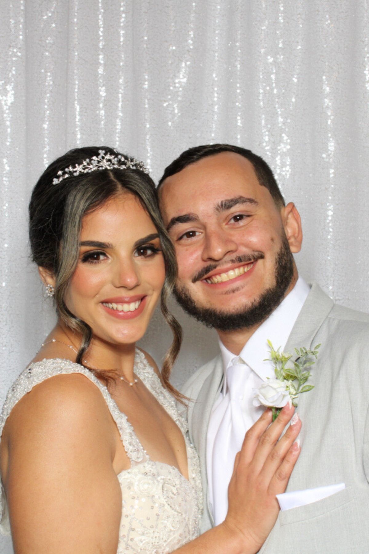A couple in wedding attire poses together in front of a white backdrop in a photo booth strip sequence.