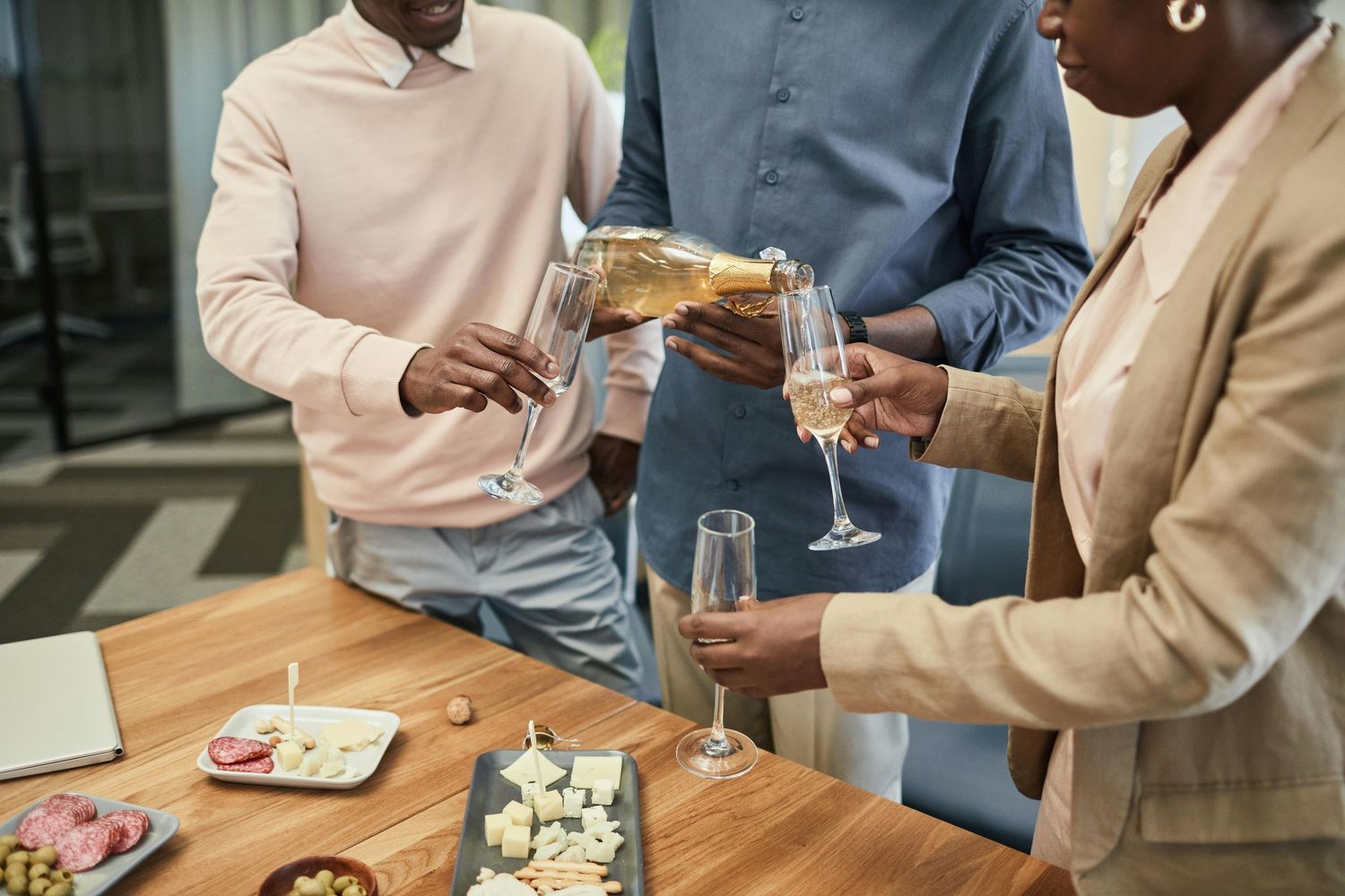 A group of people enjoying sushi and drinks at a casual dining gathering around a wooden table.