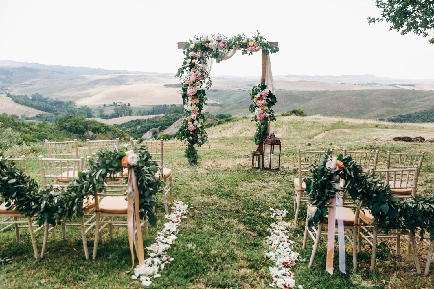 Outdoor wedding arch setup with floral decorations in a scenic mountain landscape.