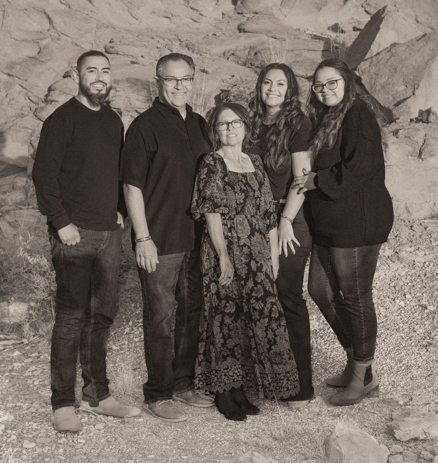 A family of five poses together against rocky terrain in a classic black and white group portrait.