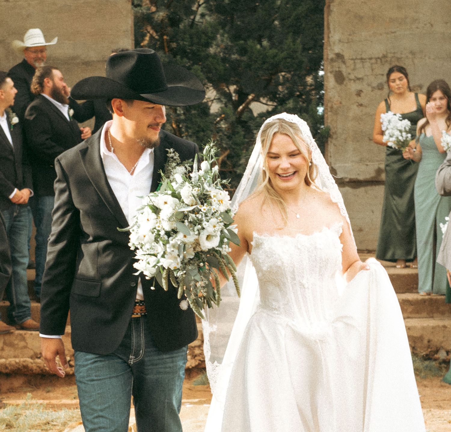 Newlyweds smiling as they walk through wedding guests.