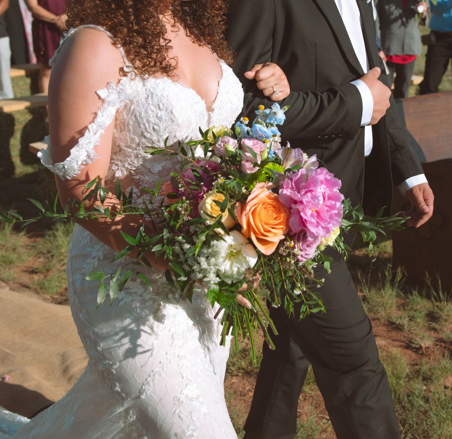 Close-up of bride holding a lush colorful wedding bouquet with pink and orange blooms.