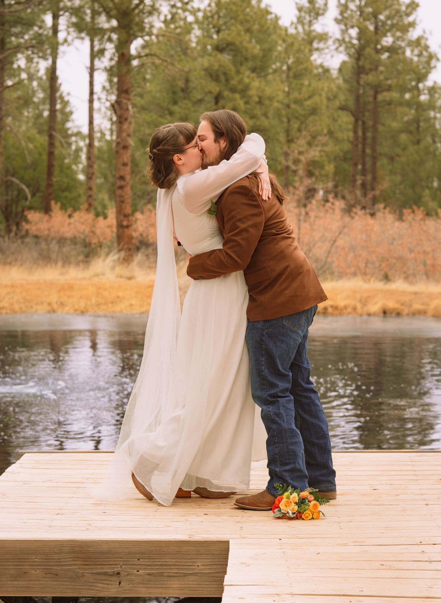 Couple sharing first kiss on wooden dock by lake in forest, Elopement in Torreon, New Mexico, Elopement at Manzano Mountain Retreat