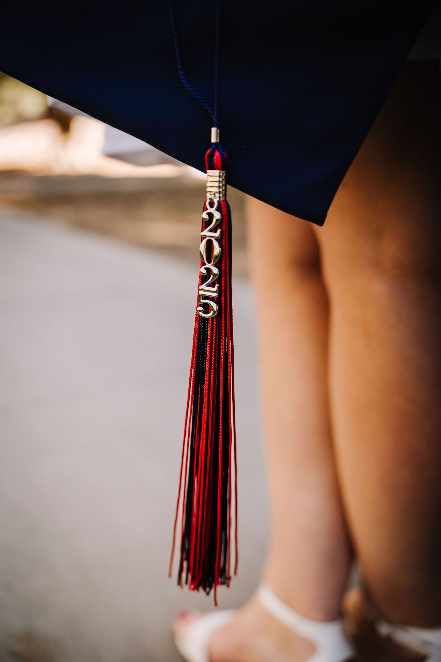 Close-up of a red and gold 2023 graduation tassel hanging from a navy blue mortarboard cap.