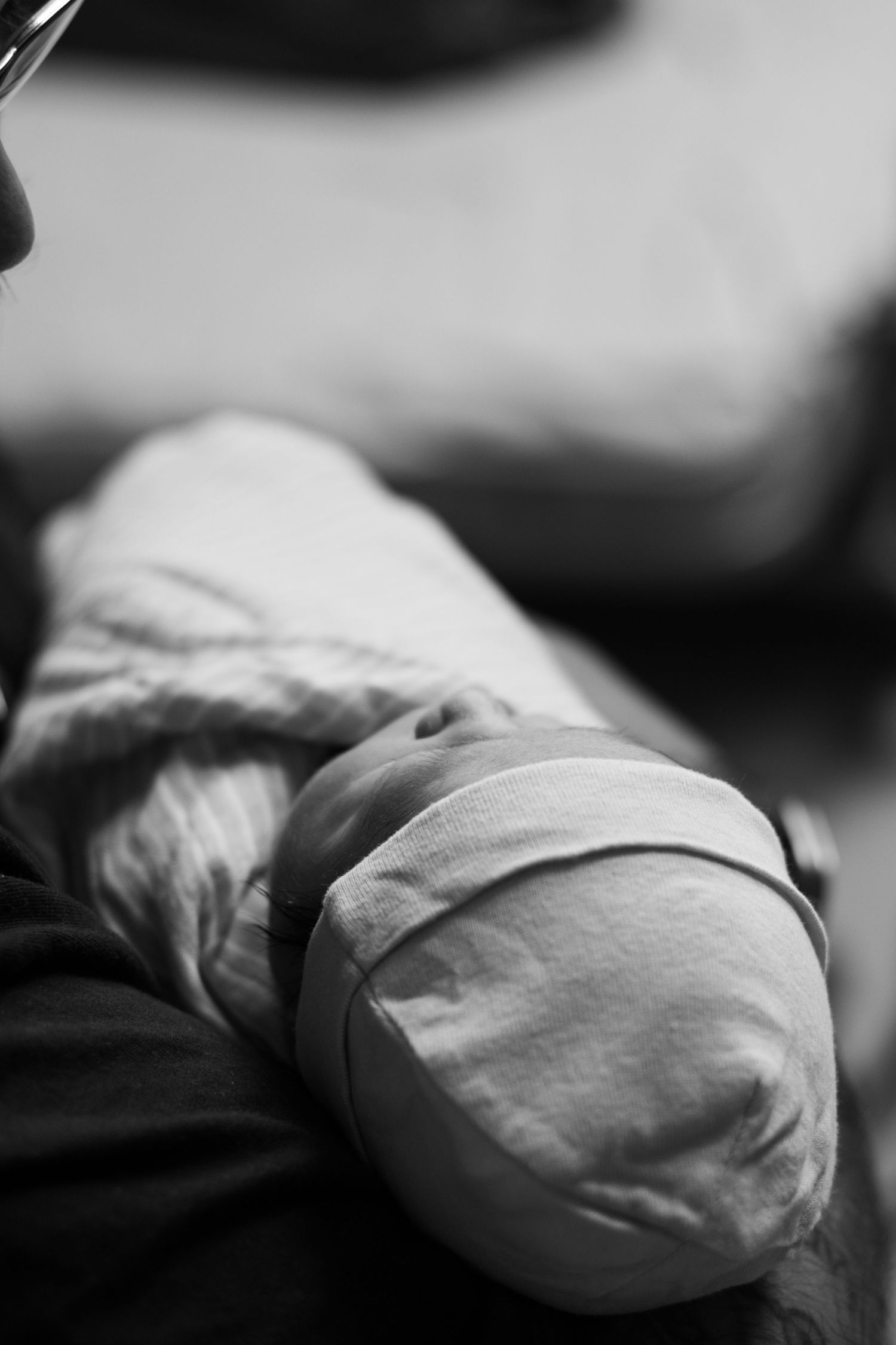 Black and white close-up of swaddled newborn baby arm with hospital identification bracelet.