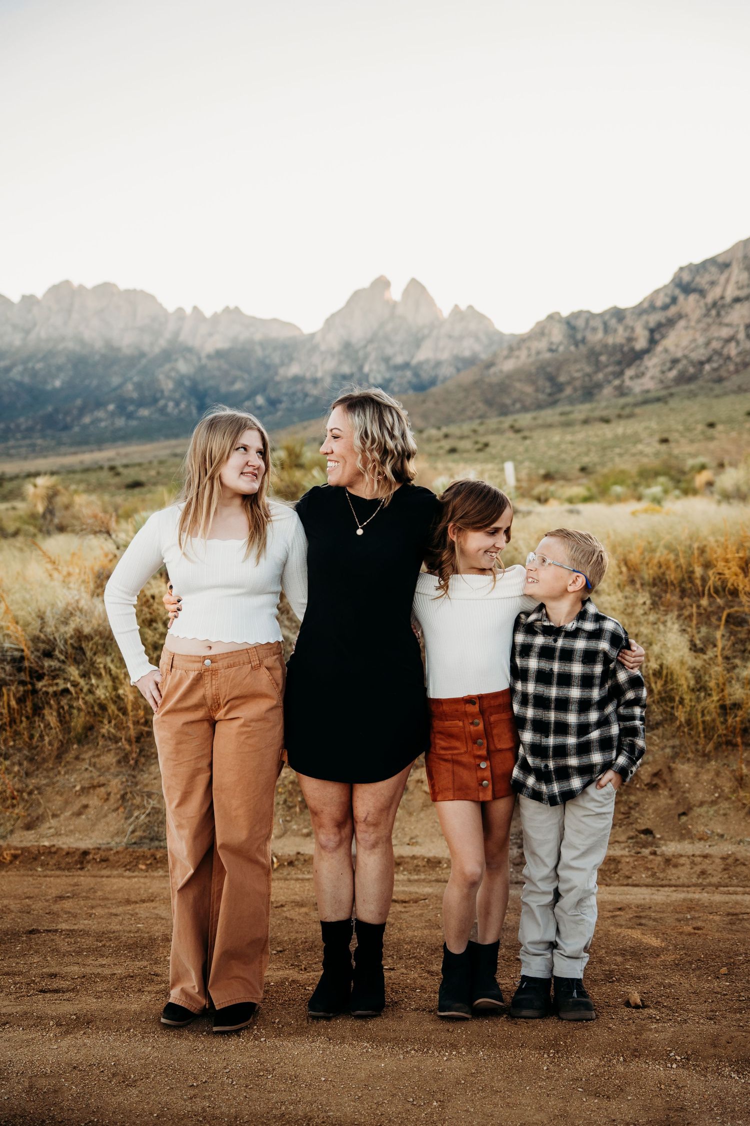 Mother and three children posing together on a dirt path with Organ Mountains backdrop.