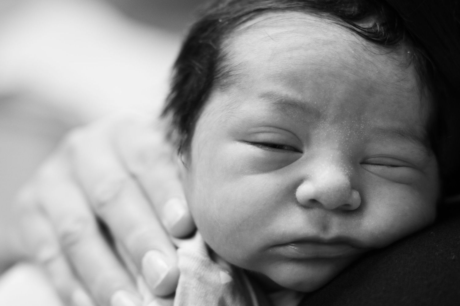 Black and white close-up portrait of peaceful sleeping newborn baby face.
