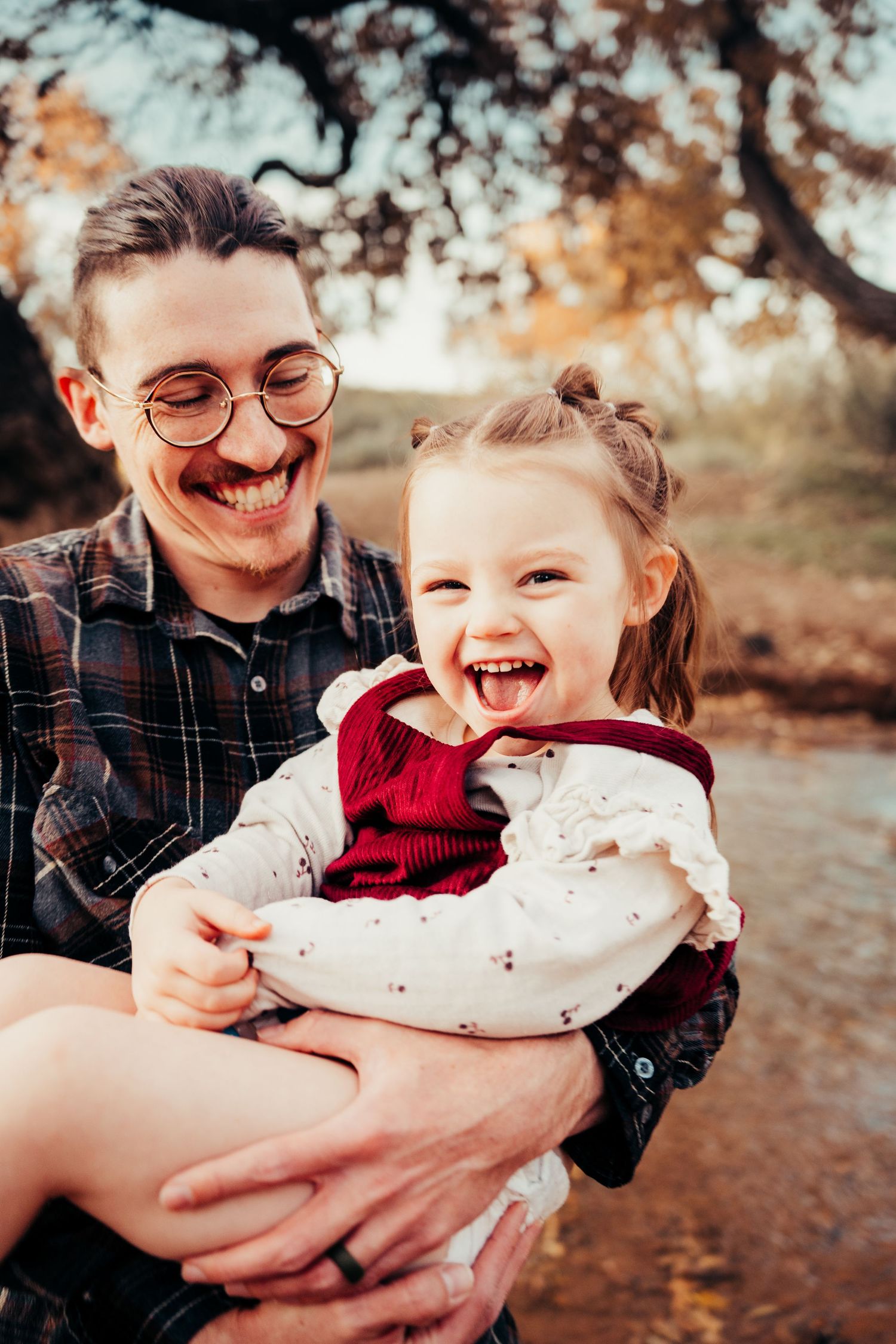 Joyful dad and excited little girl share happy moment in fall nature park.