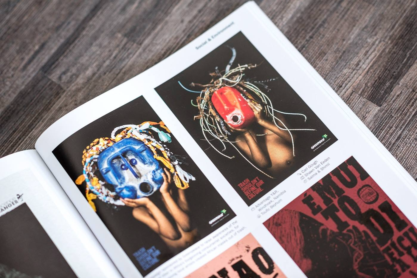 Open magazine displaying colorful graphic design artwork pages on a wooden surface.