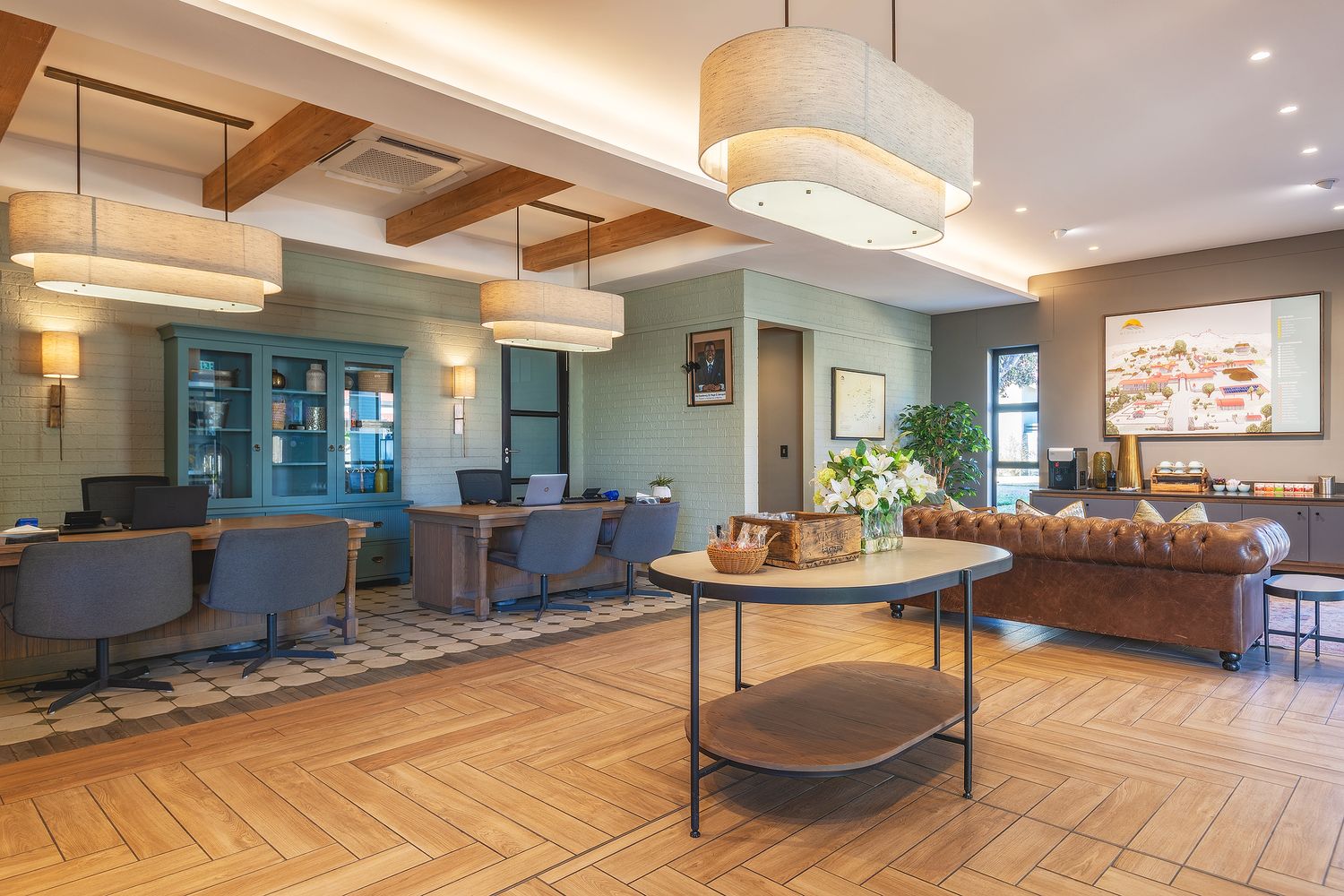 Modern hotel lobby with herringbone floors, pendant lights, teal cabinetry, and elegant seating areas.