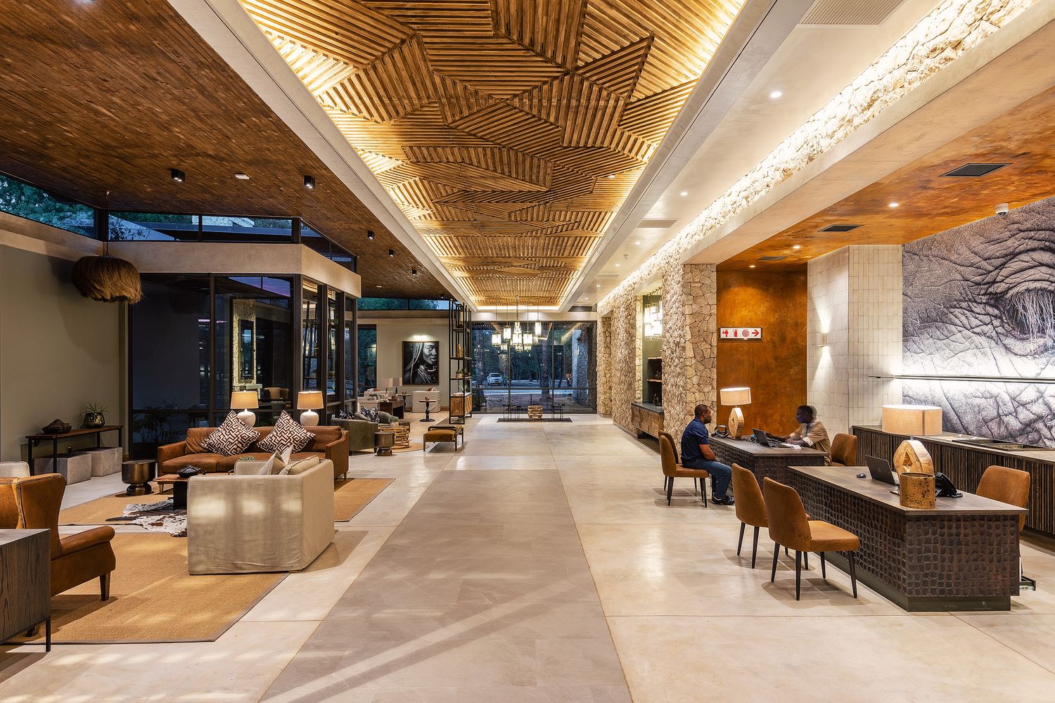 Elegant hotel lobby with wooden ceiling, stone walls, ambient lighting, and modern lounge seating area.