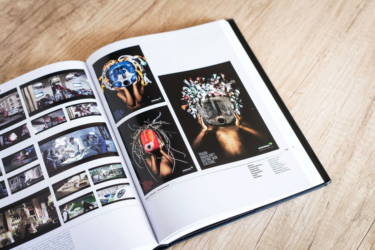Open hardcover photography book displaying colorful editorial spreads with artistic portraits on a wooden surface.