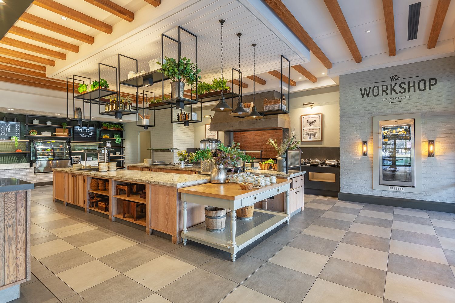 Modern restaurant kitchen workshop with wooden counters, hanging plants, pendant lights, and fresh ingredients on display.