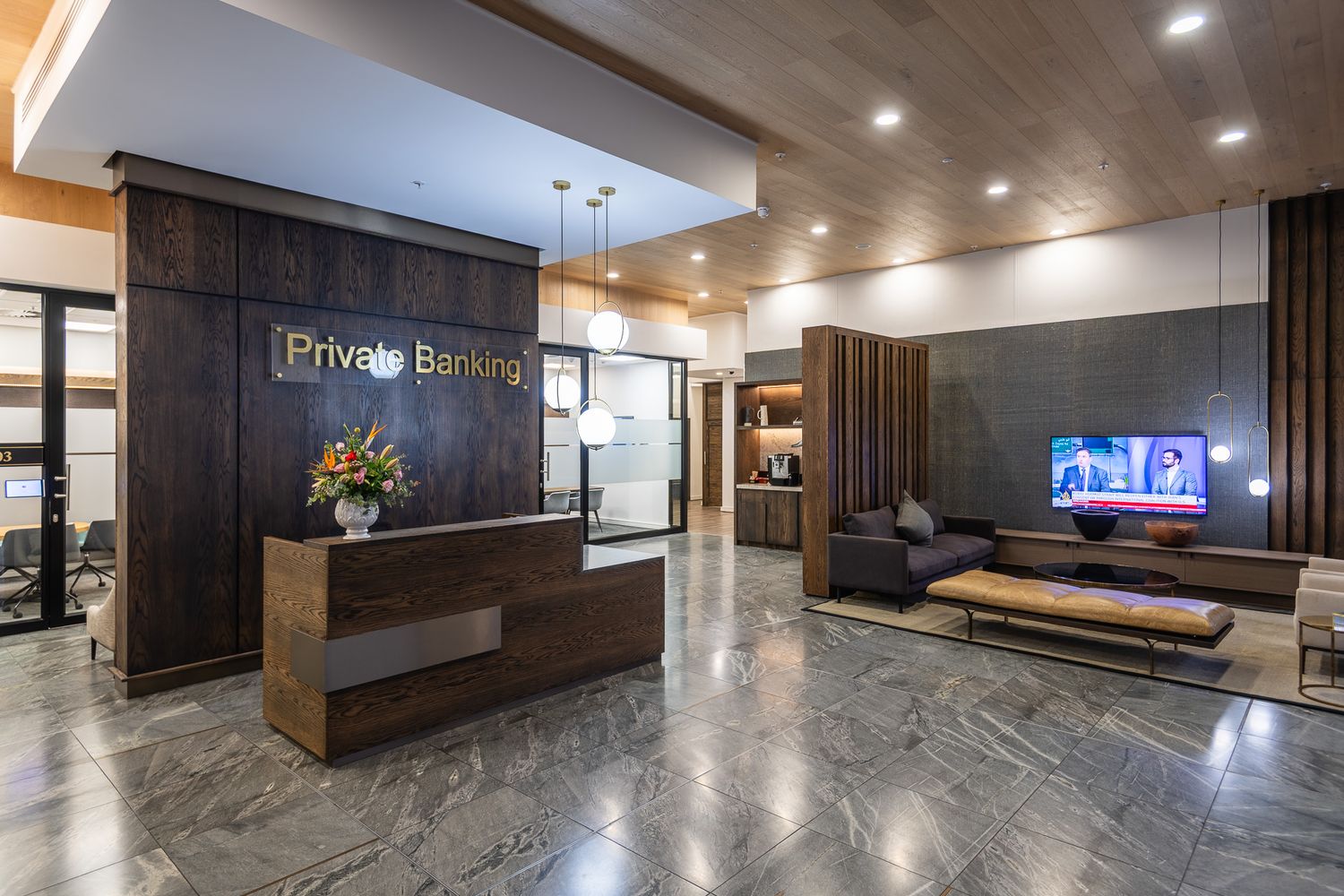 Elegant private banking lobby with marble floors, wooden reception desk, and modern lounge area with TV display.