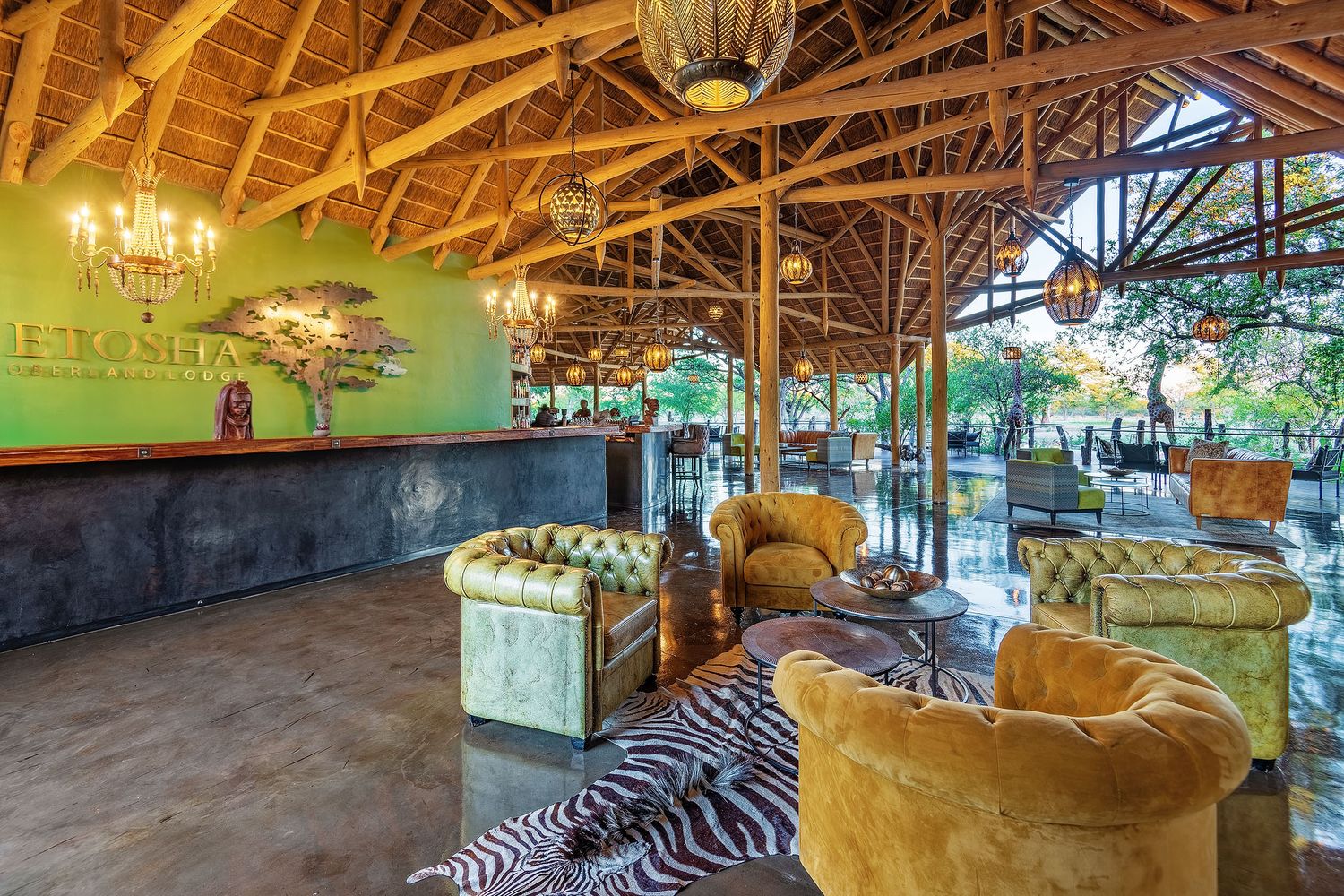 Luxurious safari lodge lobby with zebra-print rug, velvet chairs, wooden beamed ceiling, and lush green accent wall.