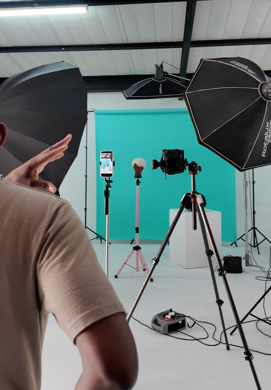 Professional photo studio setup with lighting equipment, tripods, and a teal backdrop for product photography.