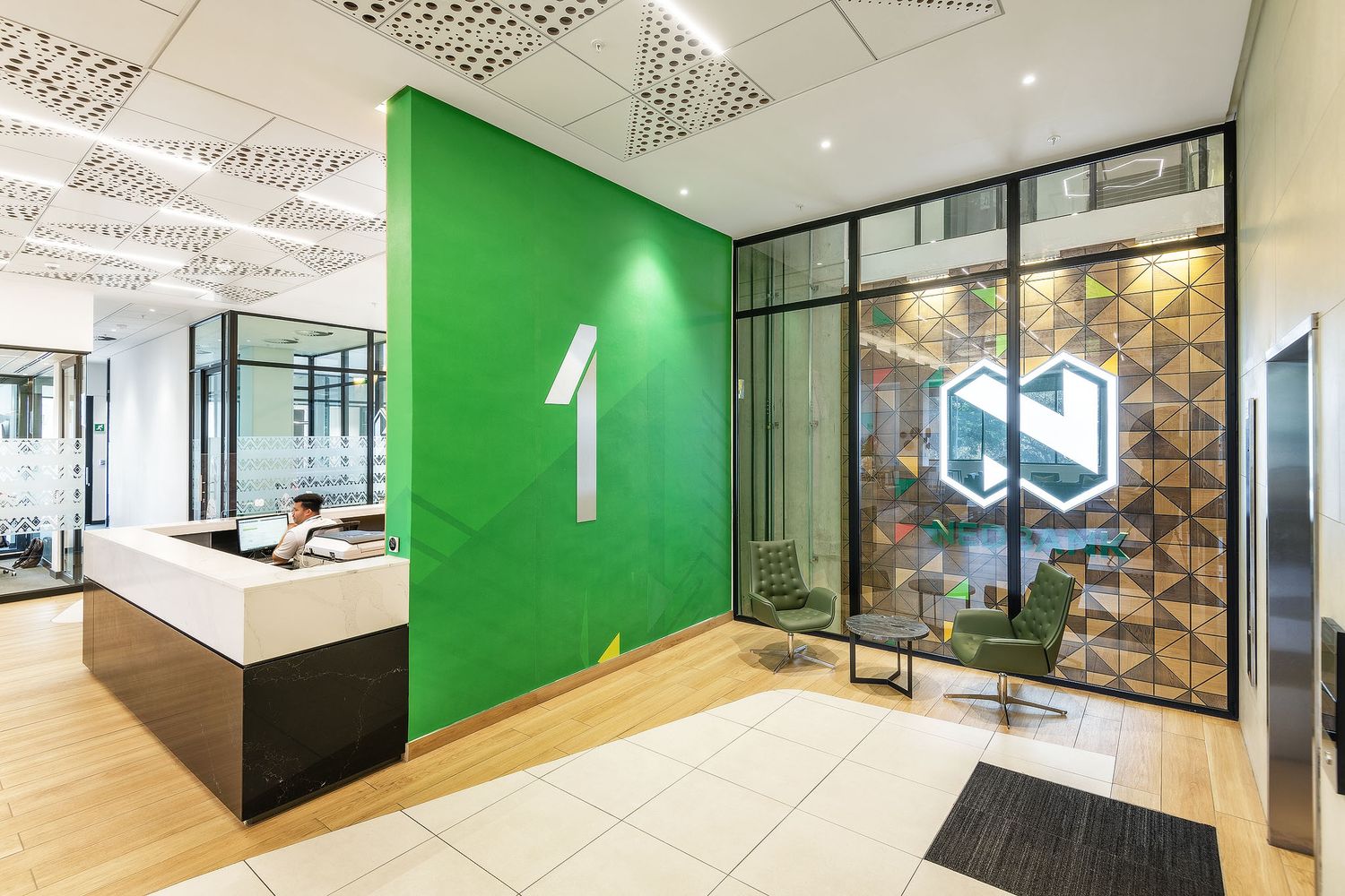 Modern office floor reception with bold green accent wall, number one signage and glass partitions.