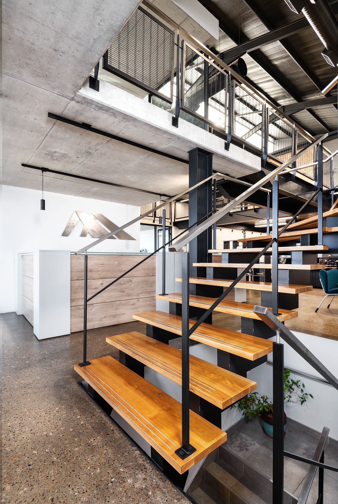 Modern industrial staircase with wooden treads and black steel frame in a contemporary open-plan loft space.
