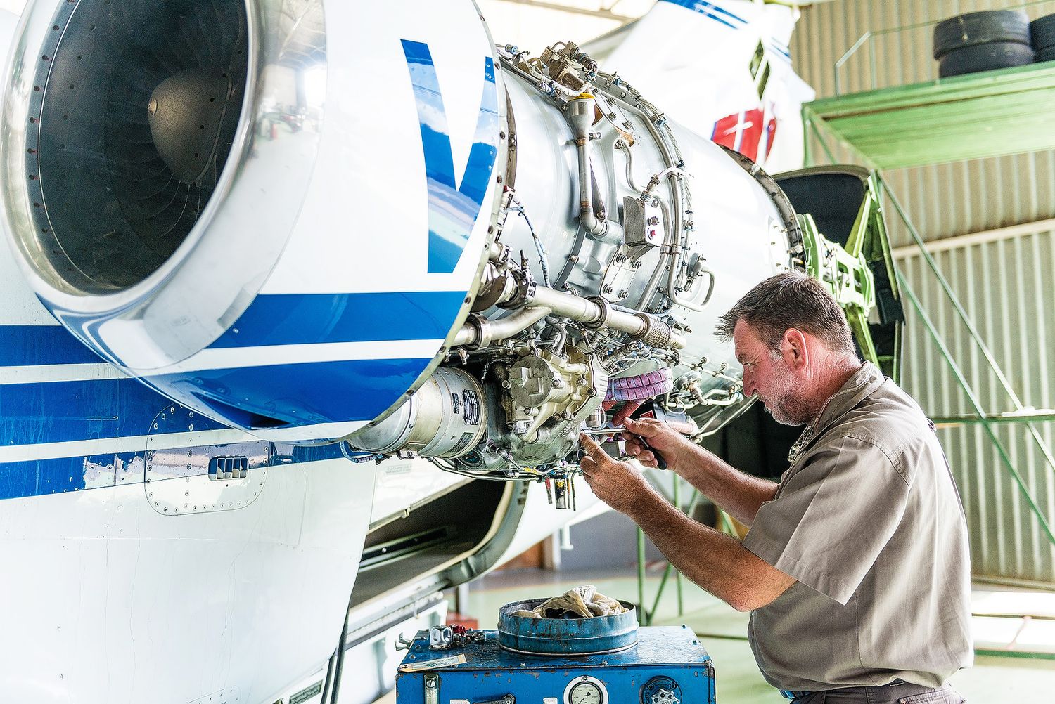 Aircraft mechanic performing maintenance on a jet engine in a hangar, inspecting complex components with precision.