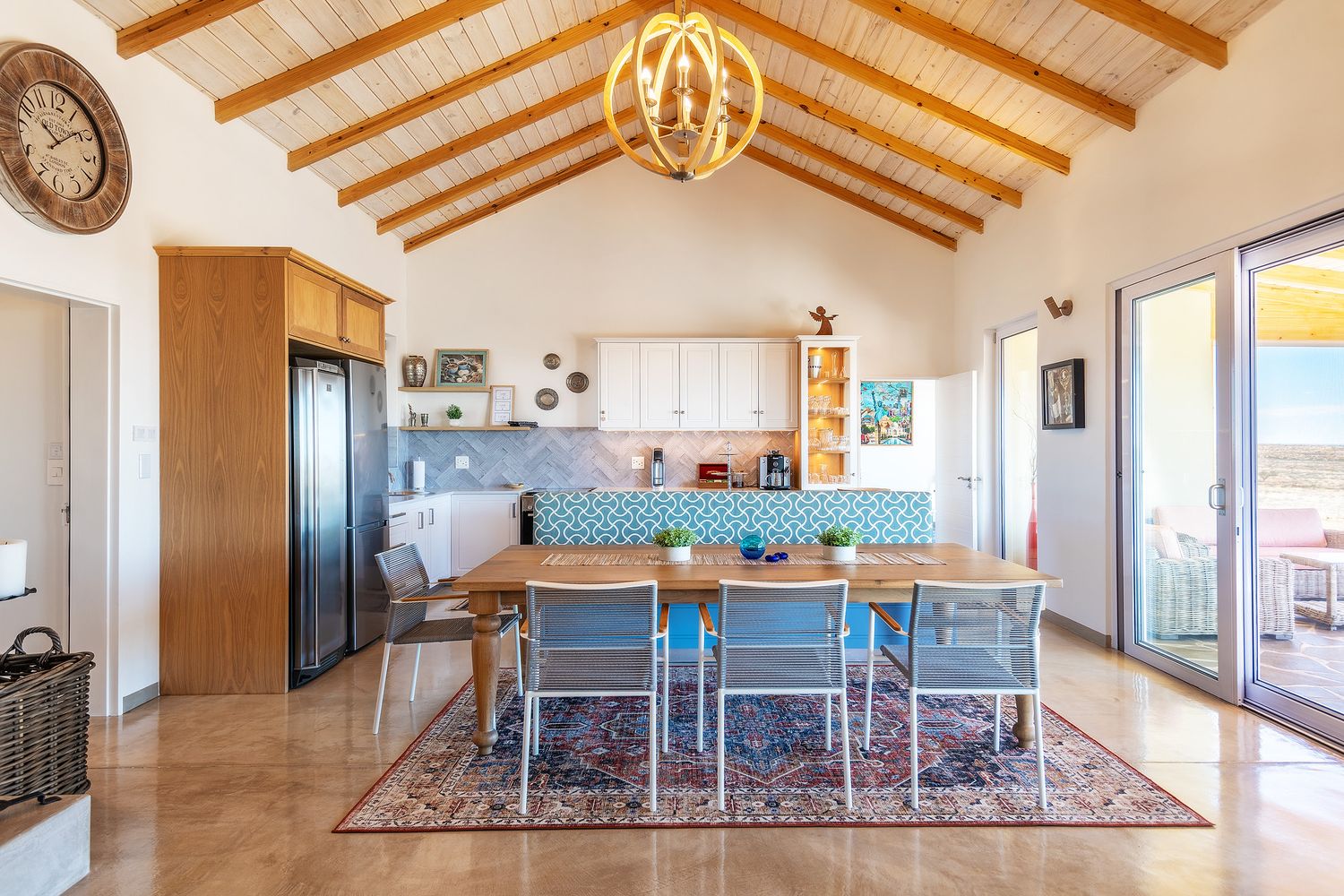 Spacious open-plan kitchen and dining area with vaulted wooden ceiling and colorful tiled backsplash in desert villa.