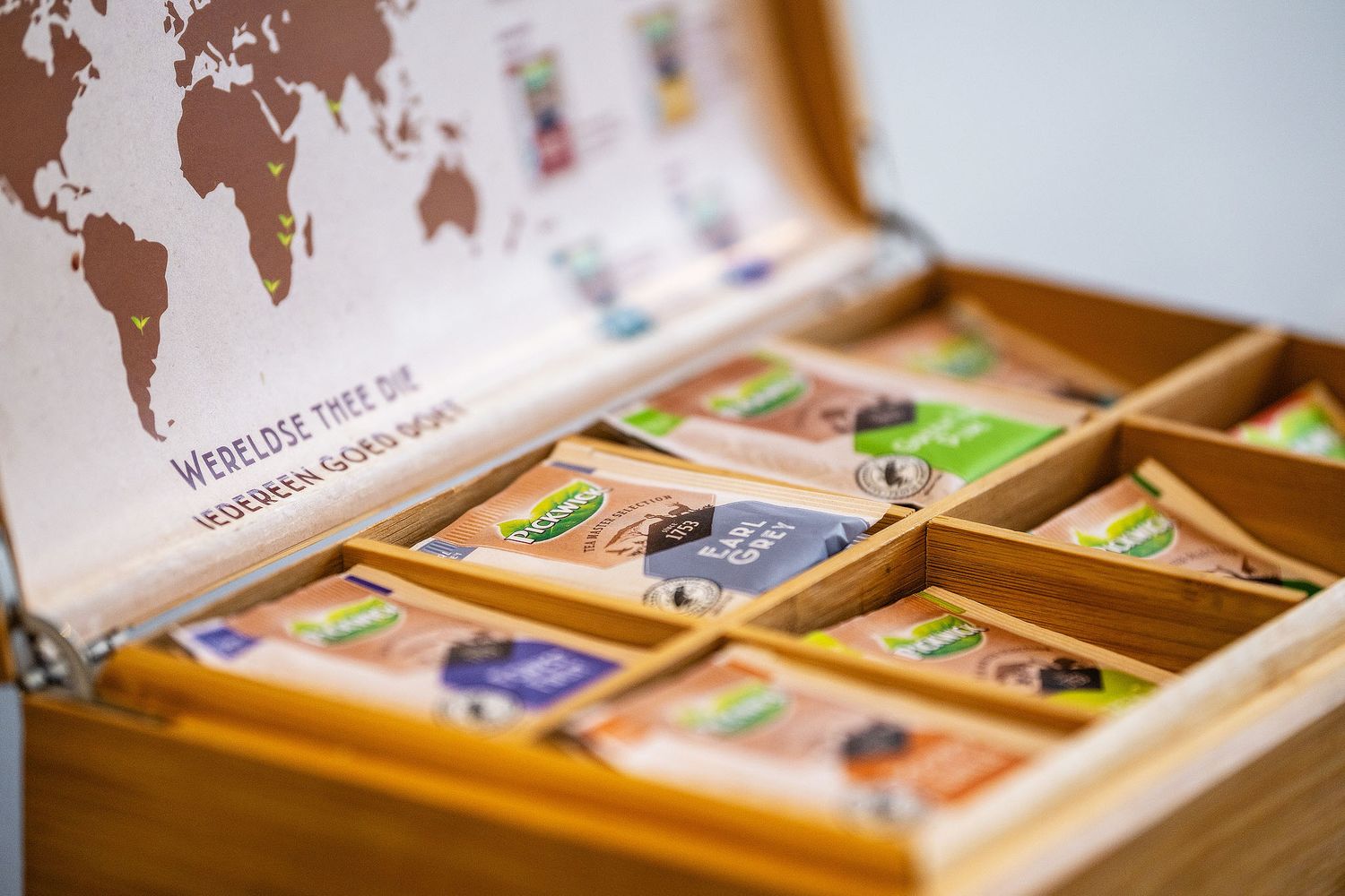 Wooden tea box with assorted Pickwick tea bags and a world map design on the lid.